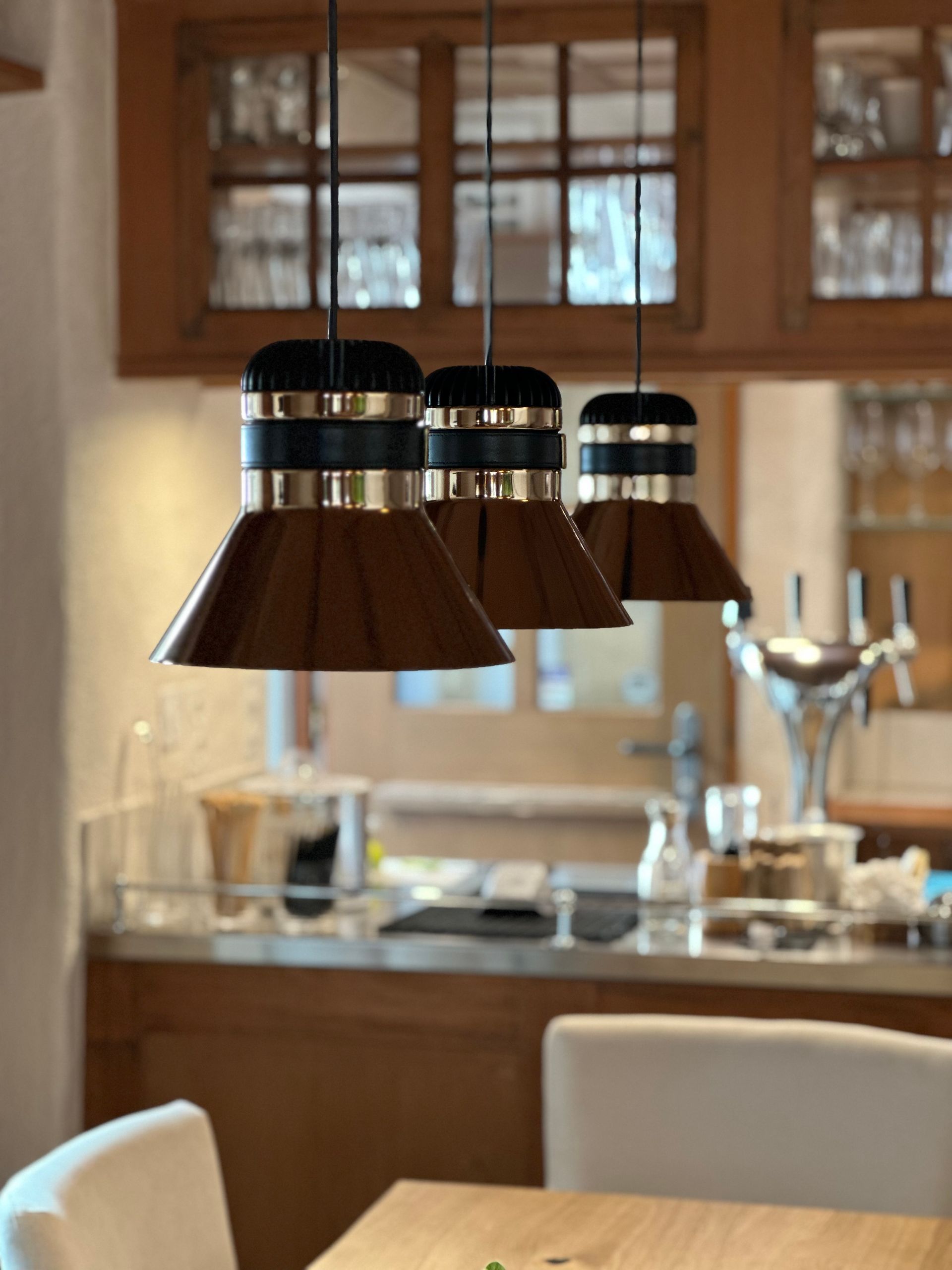 Eine Küche mit Tisch und Stühlen und ein paar Lampen, die von der Decke hängen