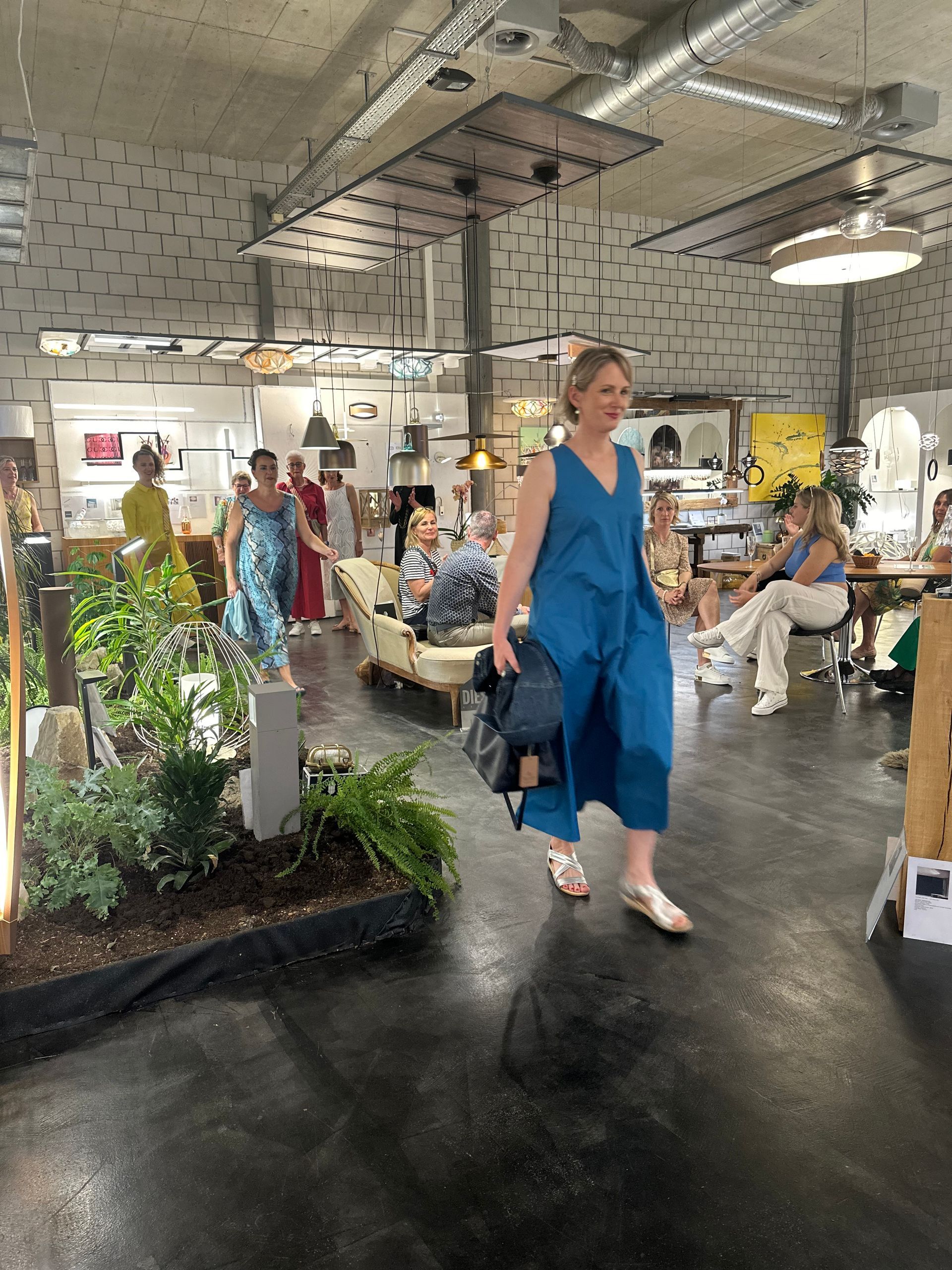 Eine Frau in einem blauen Kleid geht durch einen überfüllten Raum.