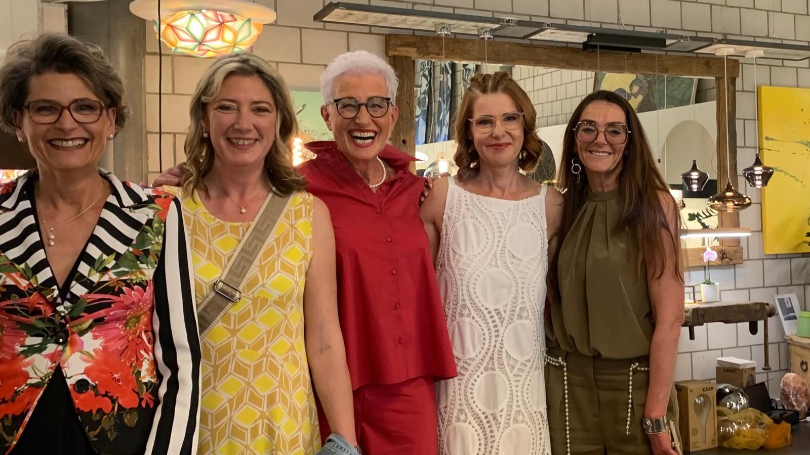 Eine Gruppe von Frauen posiert gemeinsam in einer Küche für ein Foto.