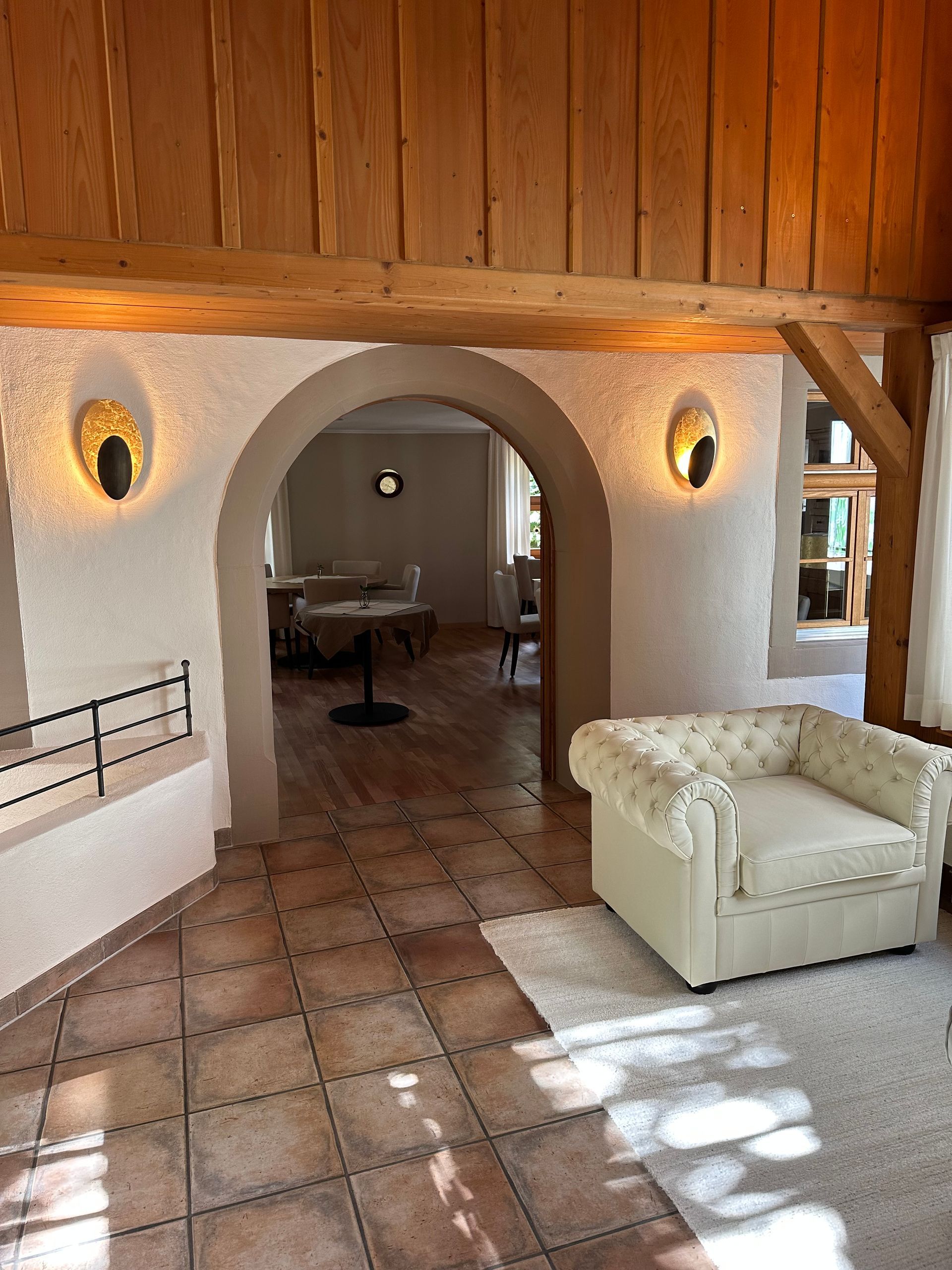 Ein Wohnzimmer mit einem weißen Stuhl und einem hölzernen Torbogen