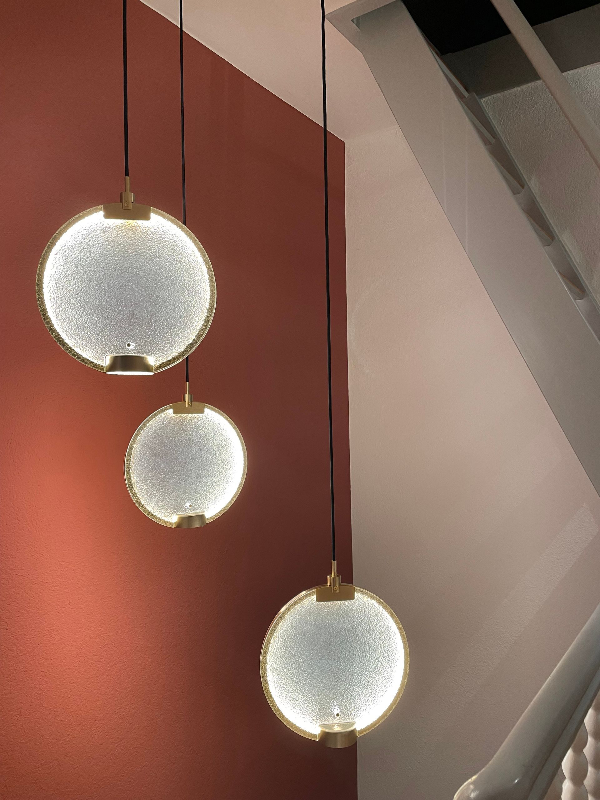 In einem Raum hängen drei Pendelleuchten von der Decke.