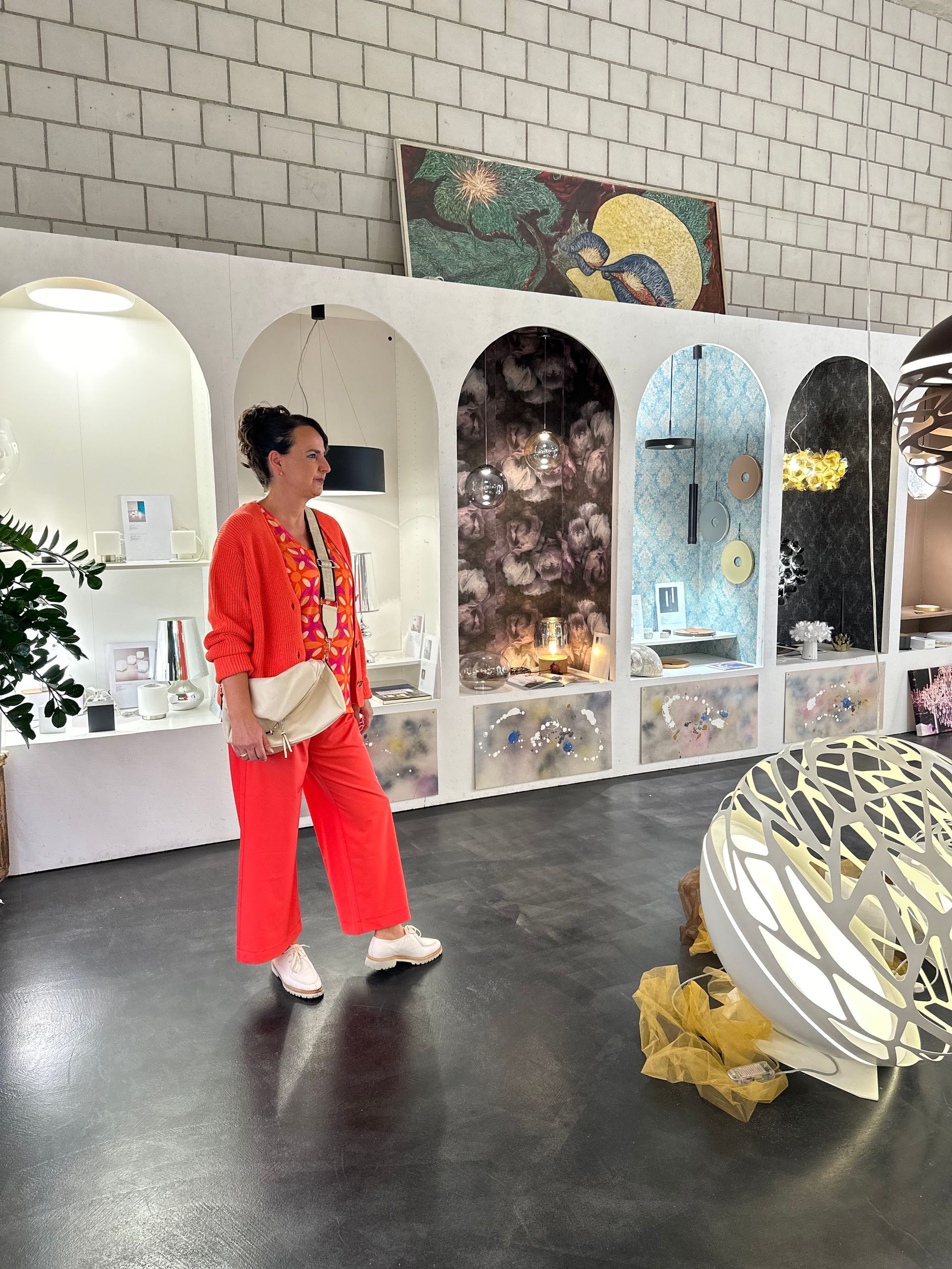Eine Frau in einem roten Pullover und roten Hosen steht in einem Raum.