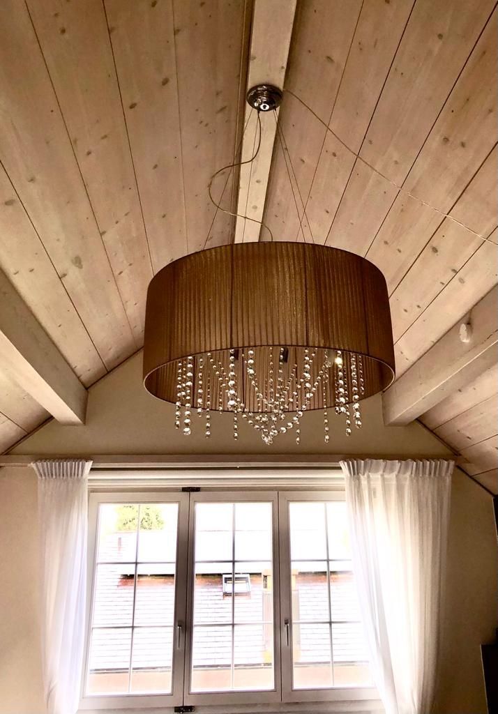 In einem Raum mit Fenster hängt ein Kronleuchter von der Decke.