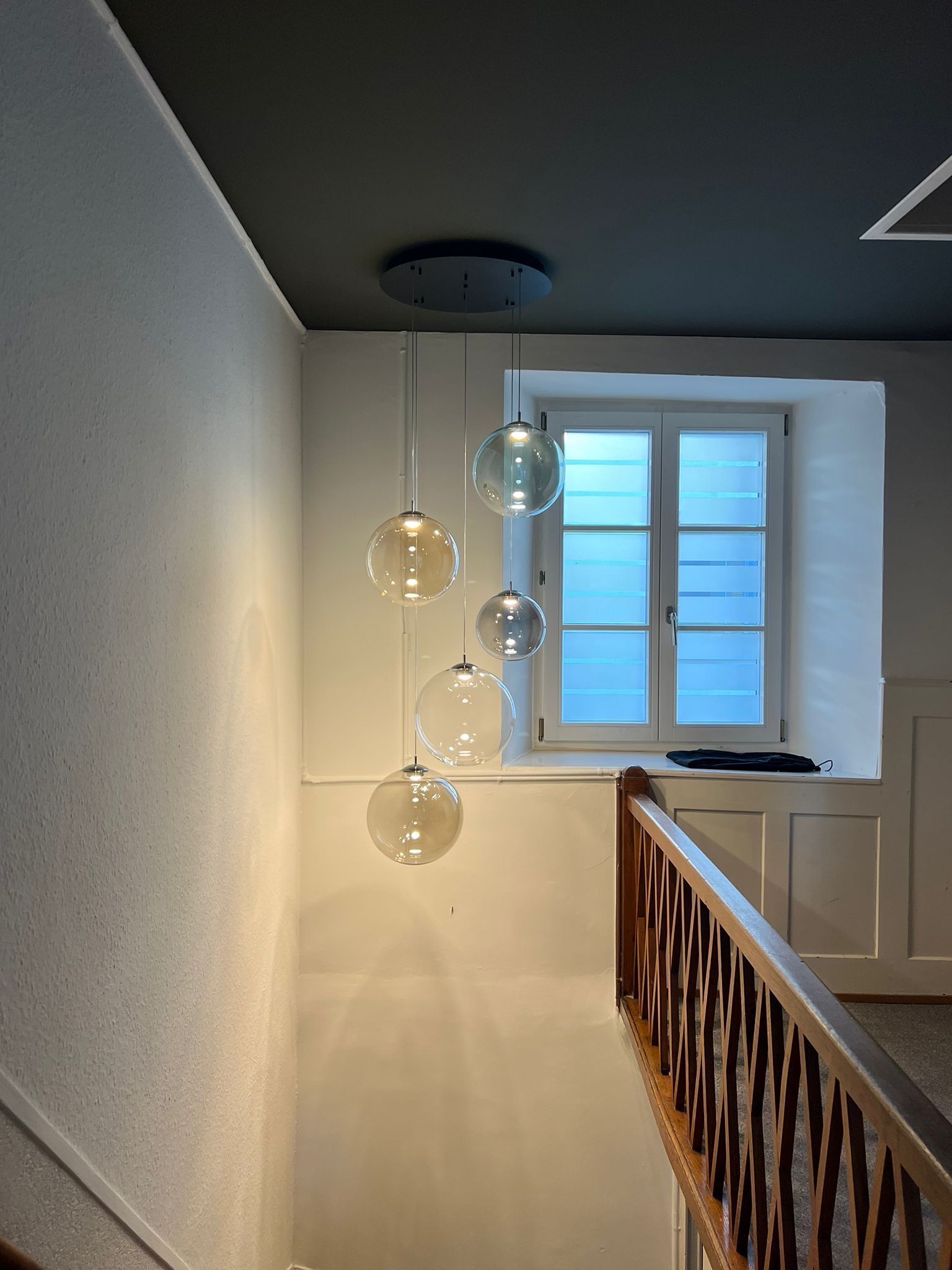 Eine Treppe mit einem Fenster und ein paar Lampen, die von der Decke hängen.