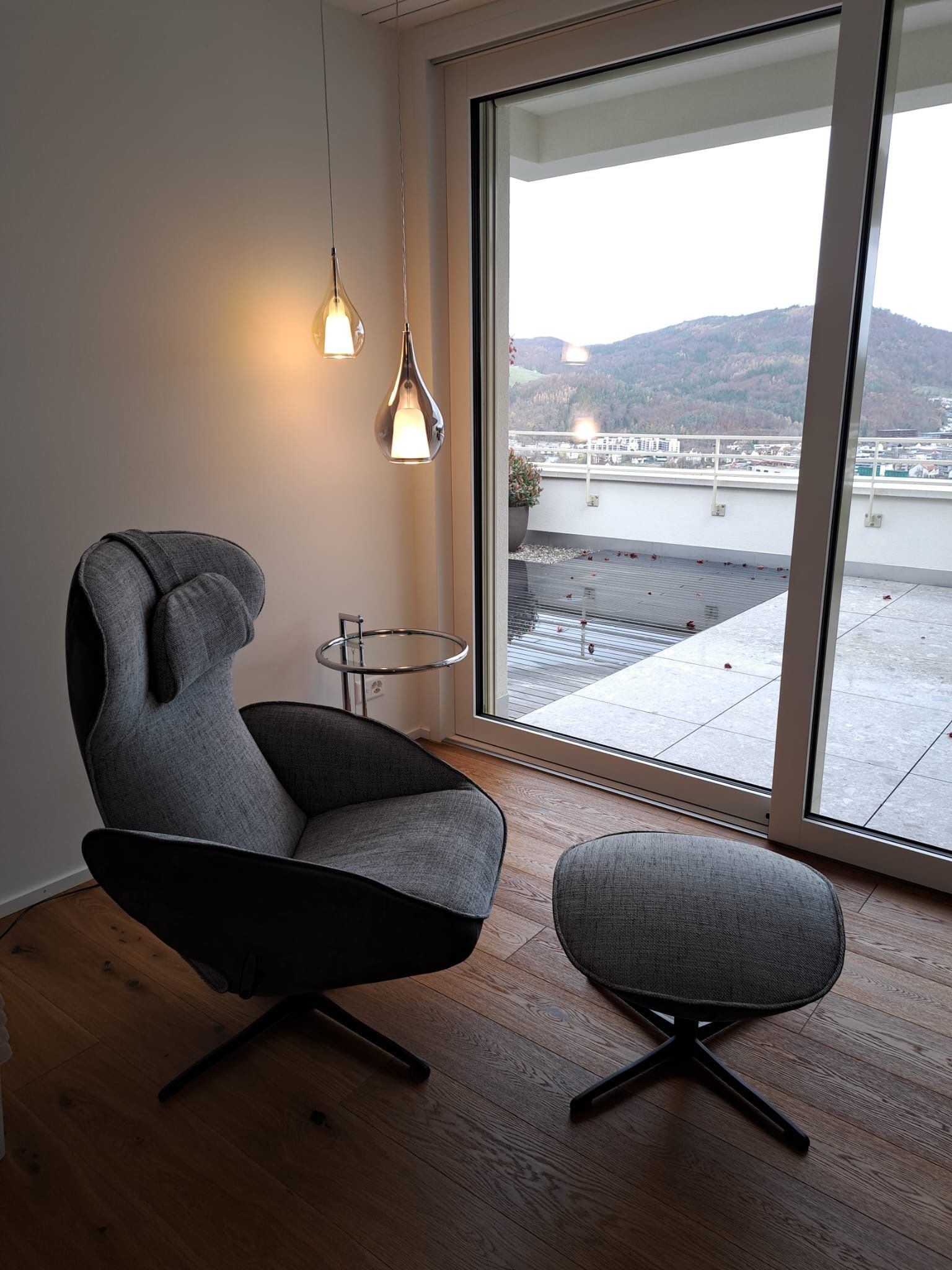 Ein Stuhl und ein Ottoman vor einem großen Fenster