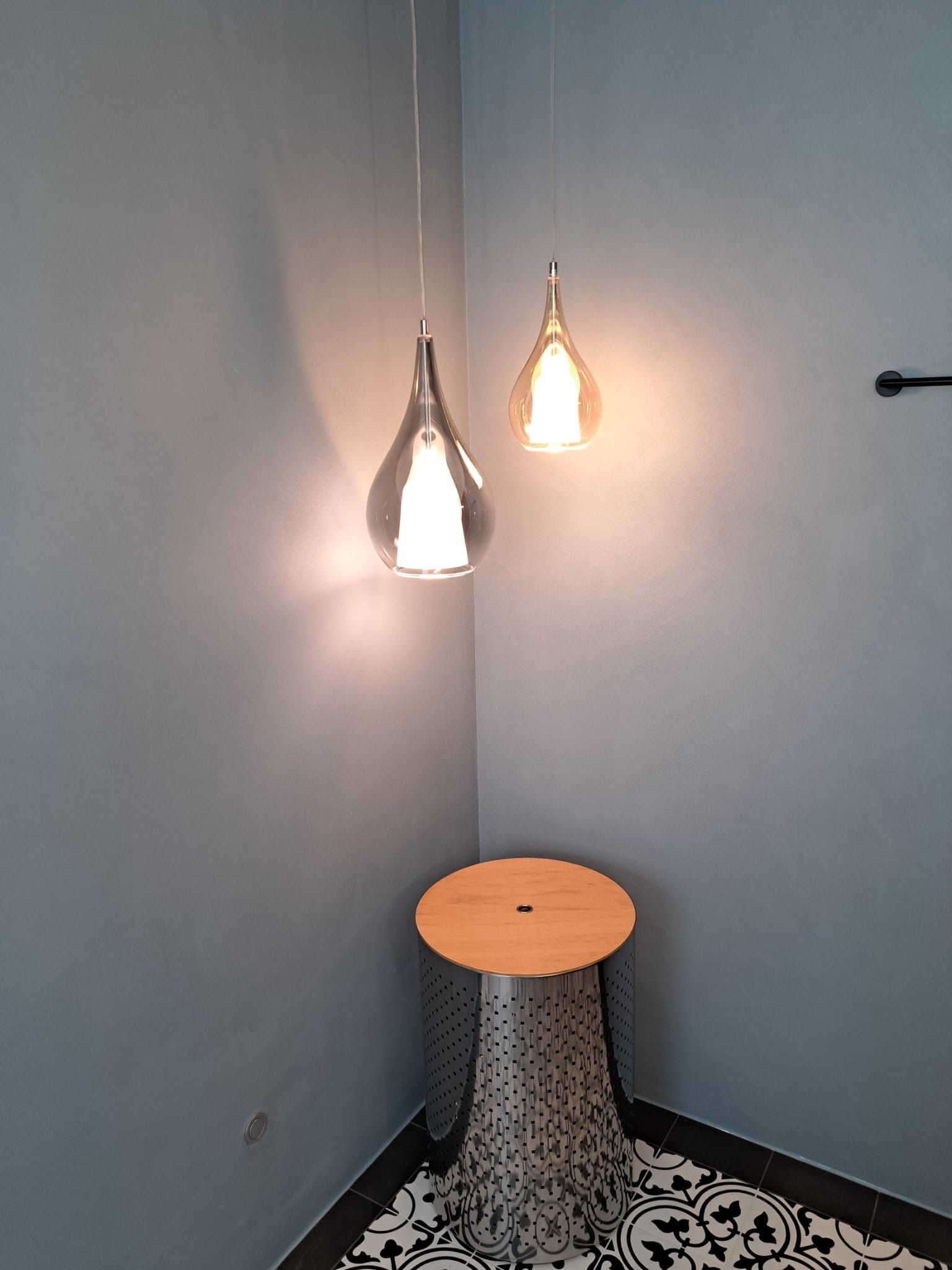 Eine Zimmerecke mit einem Tisch und zwei Lampen, die von der Decke hängen.