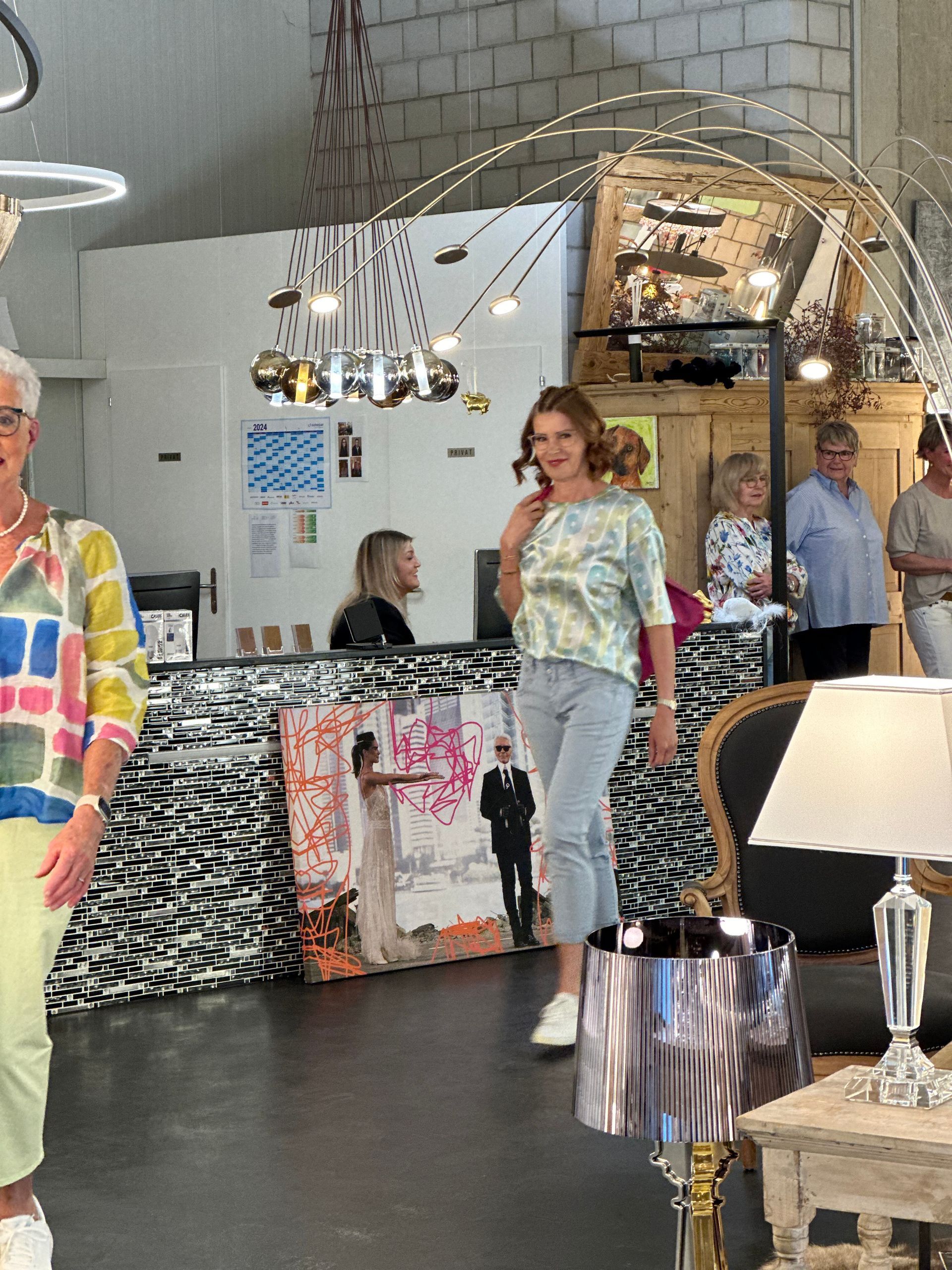 Eine Gruppe von Menschen steht in einem Raum mit Lampen und Gemälden