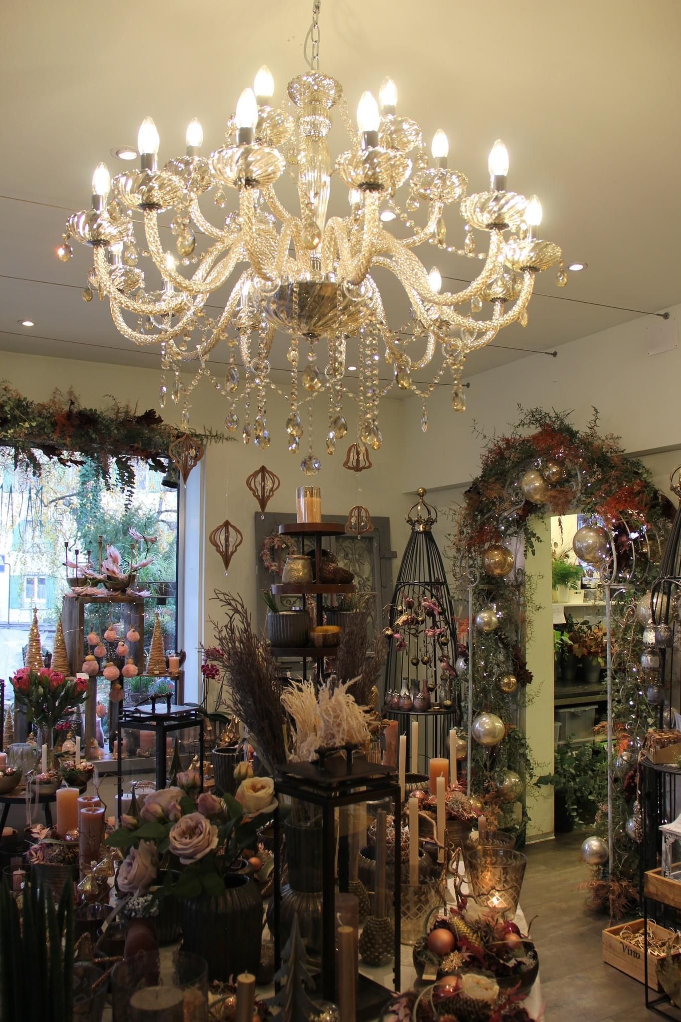 In einem Raum voller Weihnachtsdekorationen hängt ein großer Kronleuchter von der Decke.