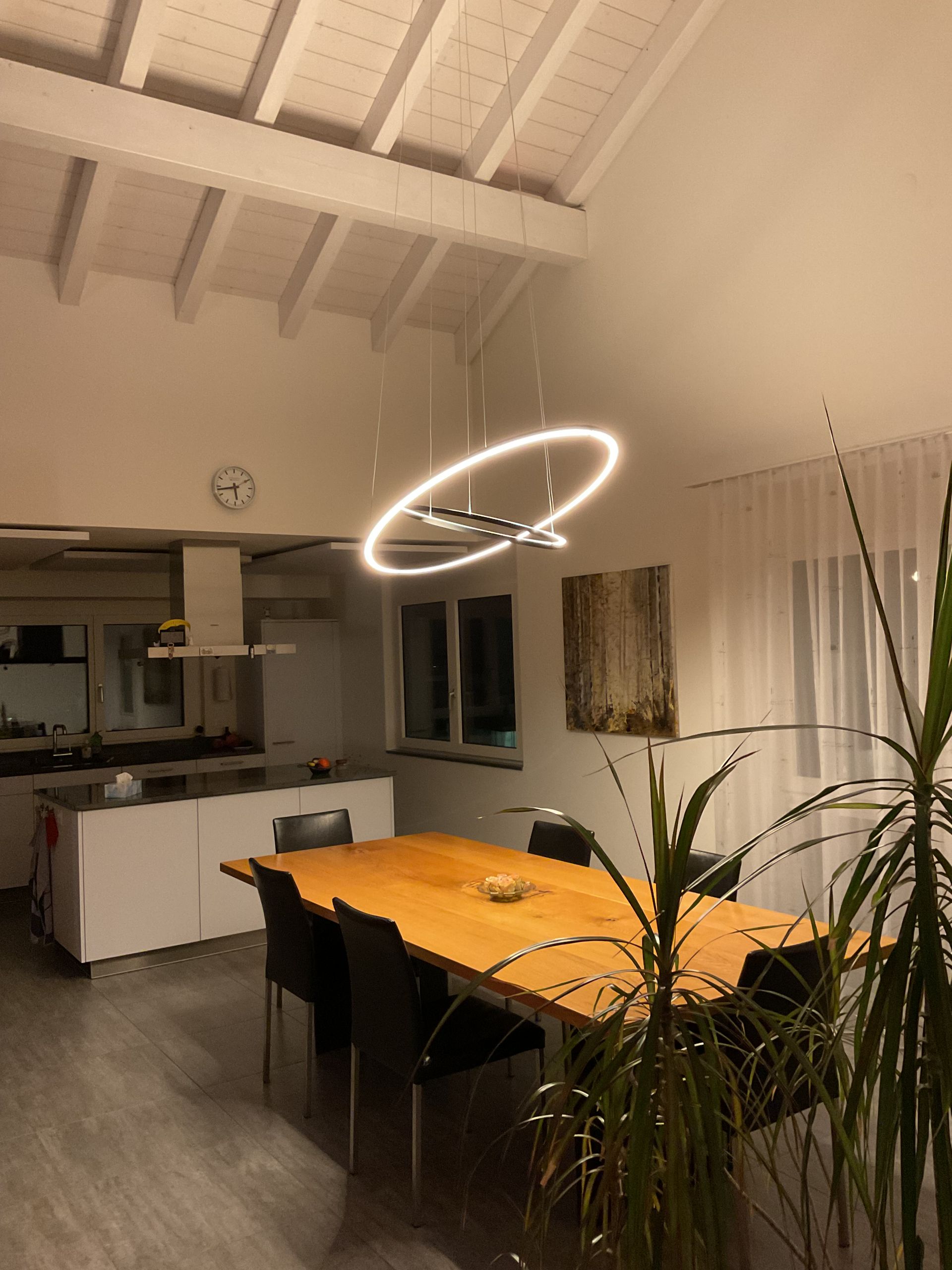 Ein Esszimmer mit Tisch und Stühlen und einer Uhr an der Wand