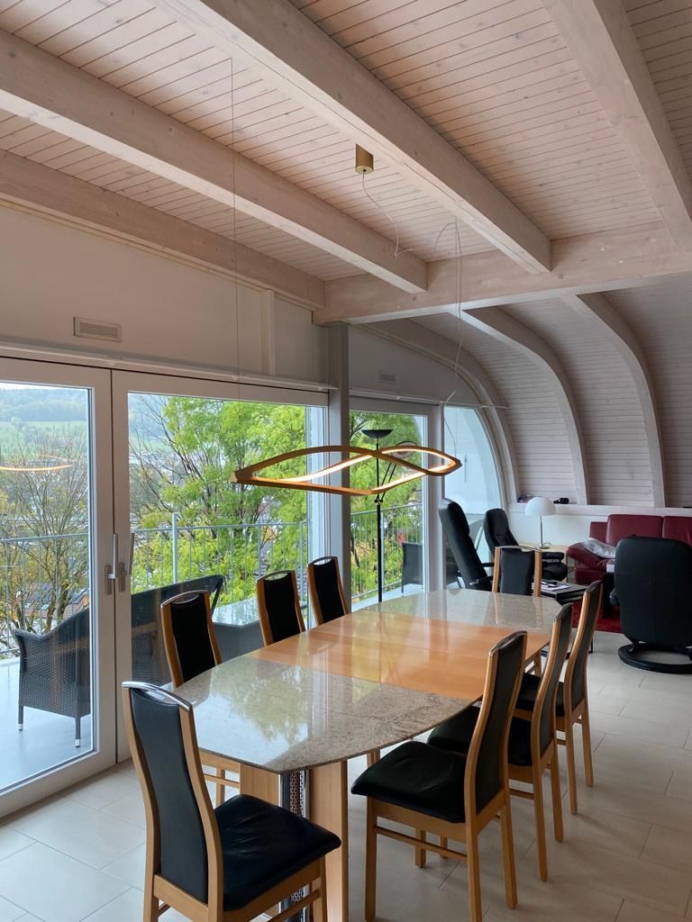 Ein Esszimmer mit einem langen Tisch und Stühlen und einem großen Fenster.