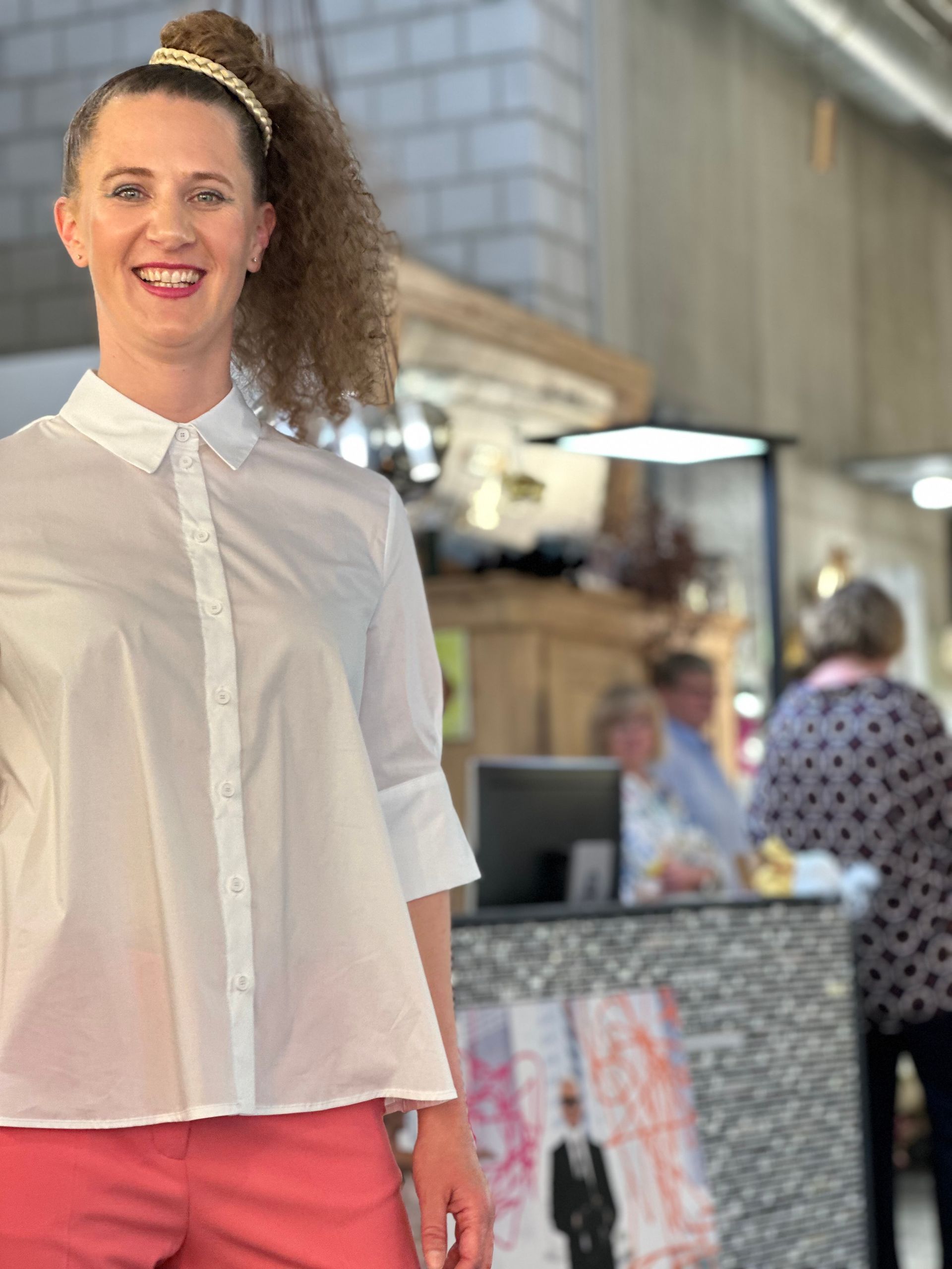 Eine Frau in einem weißen Hemd und rosa Shorts steht vor einer Ladentheke.