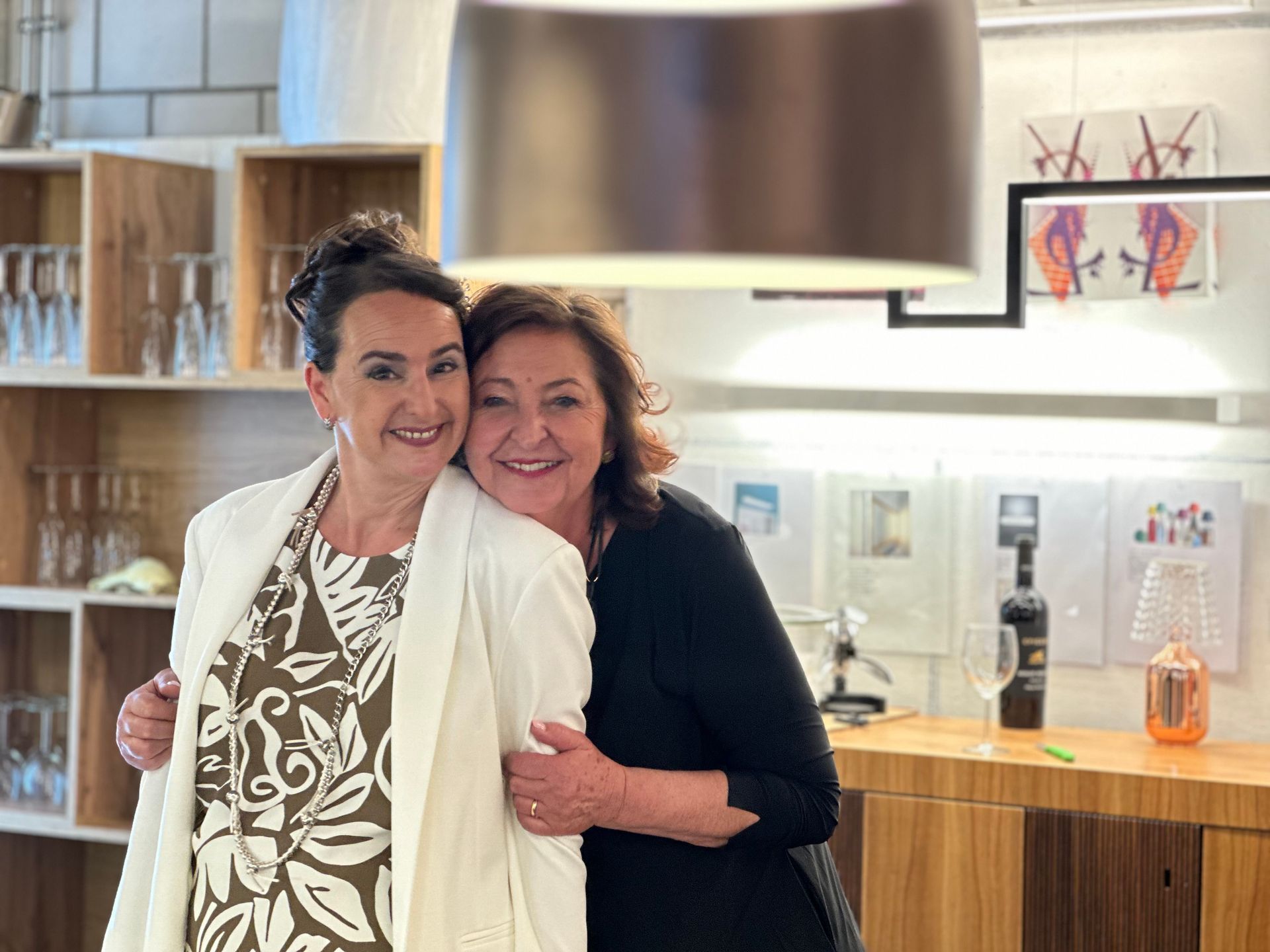 Zwei Frauen posieren zusammen für ein Foto in einer Küche.