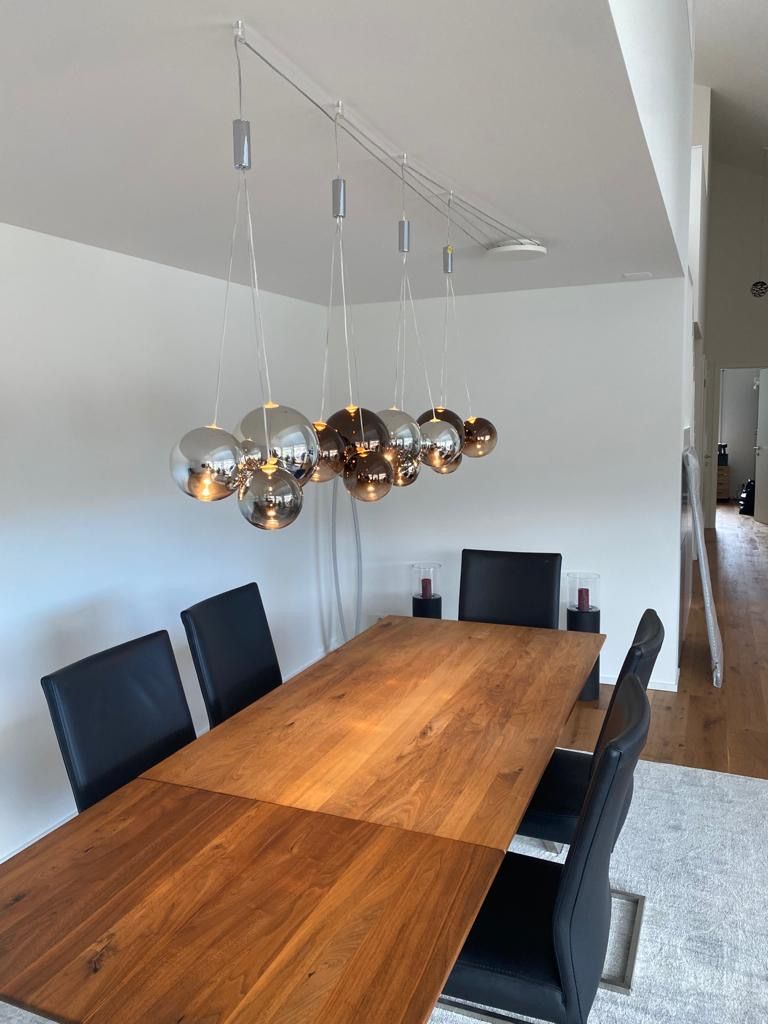 Ein Esszimmer mit einem Holztisch und Stühlen und einem Kronleuchter, der von der Decke hängt.