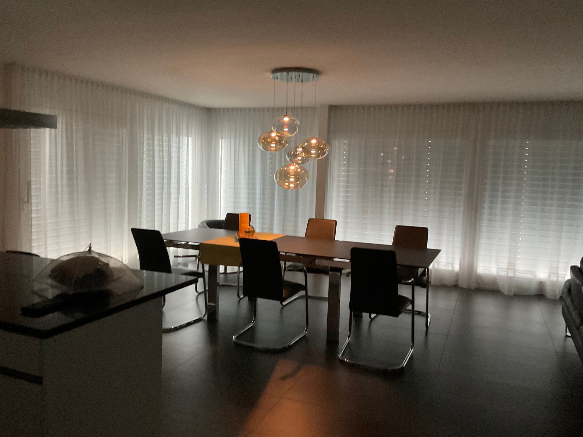 Ein Esszimmer mit Tisch und Stühlen und weißen Vorhängen