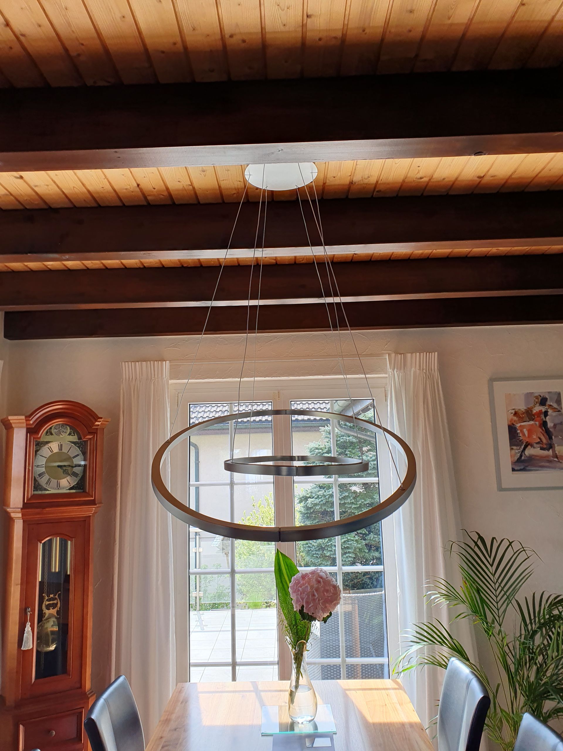 Ein Esszimmer mit einer großen Standuhr und einem Kronleuchter, der von der Decke hängt.