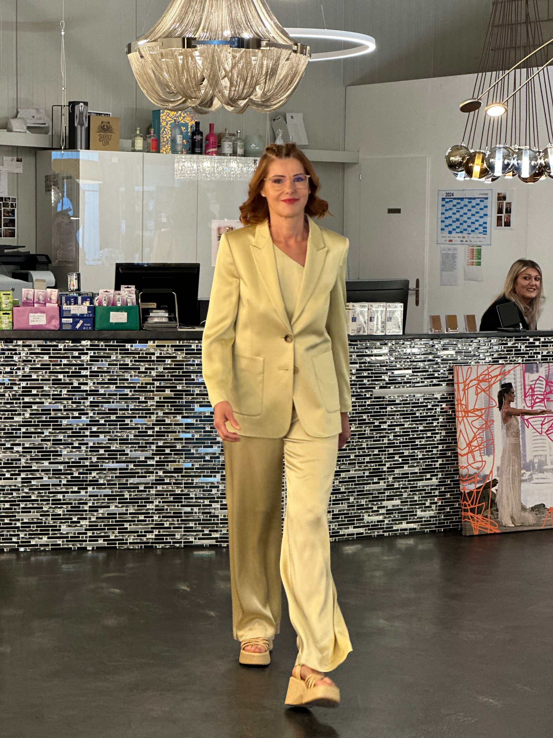 Eine Frau in einem gelben Anzug geht in einen Raum.
