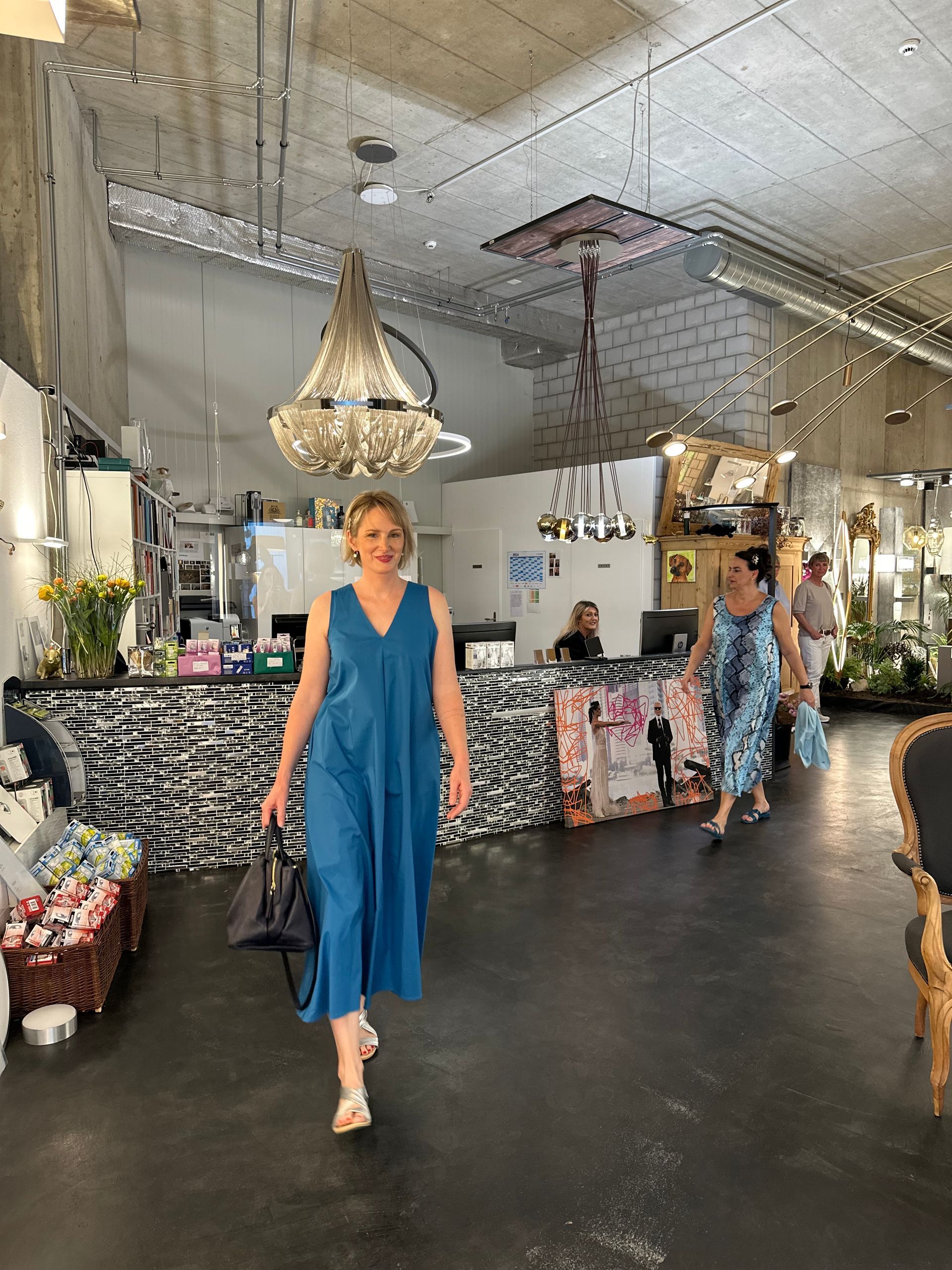 Eine Frau in einem blauen Kleid geht durch ein Geschäft.