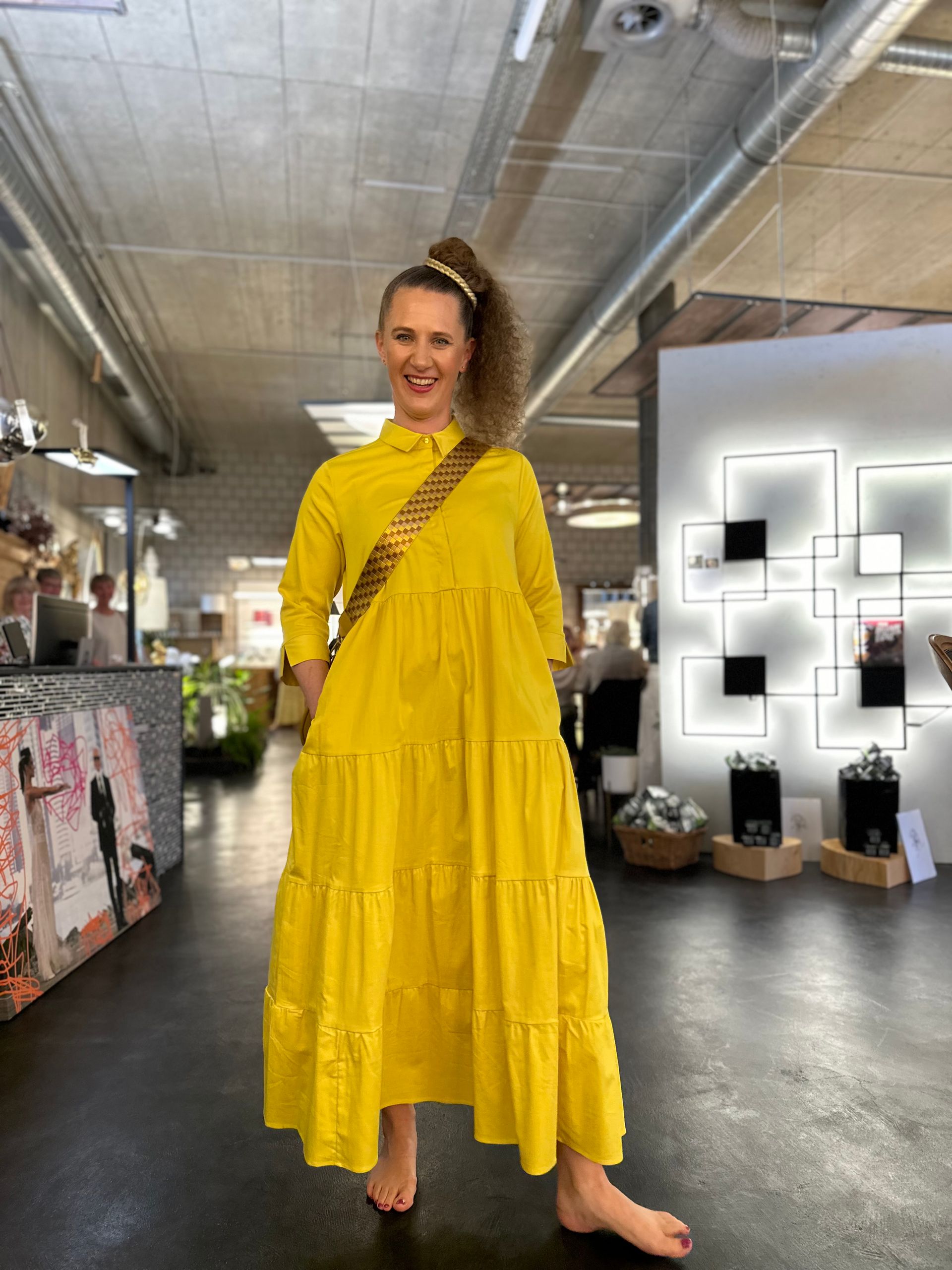 Eine Frau in einem gelben Kleid steht in einem Raum.