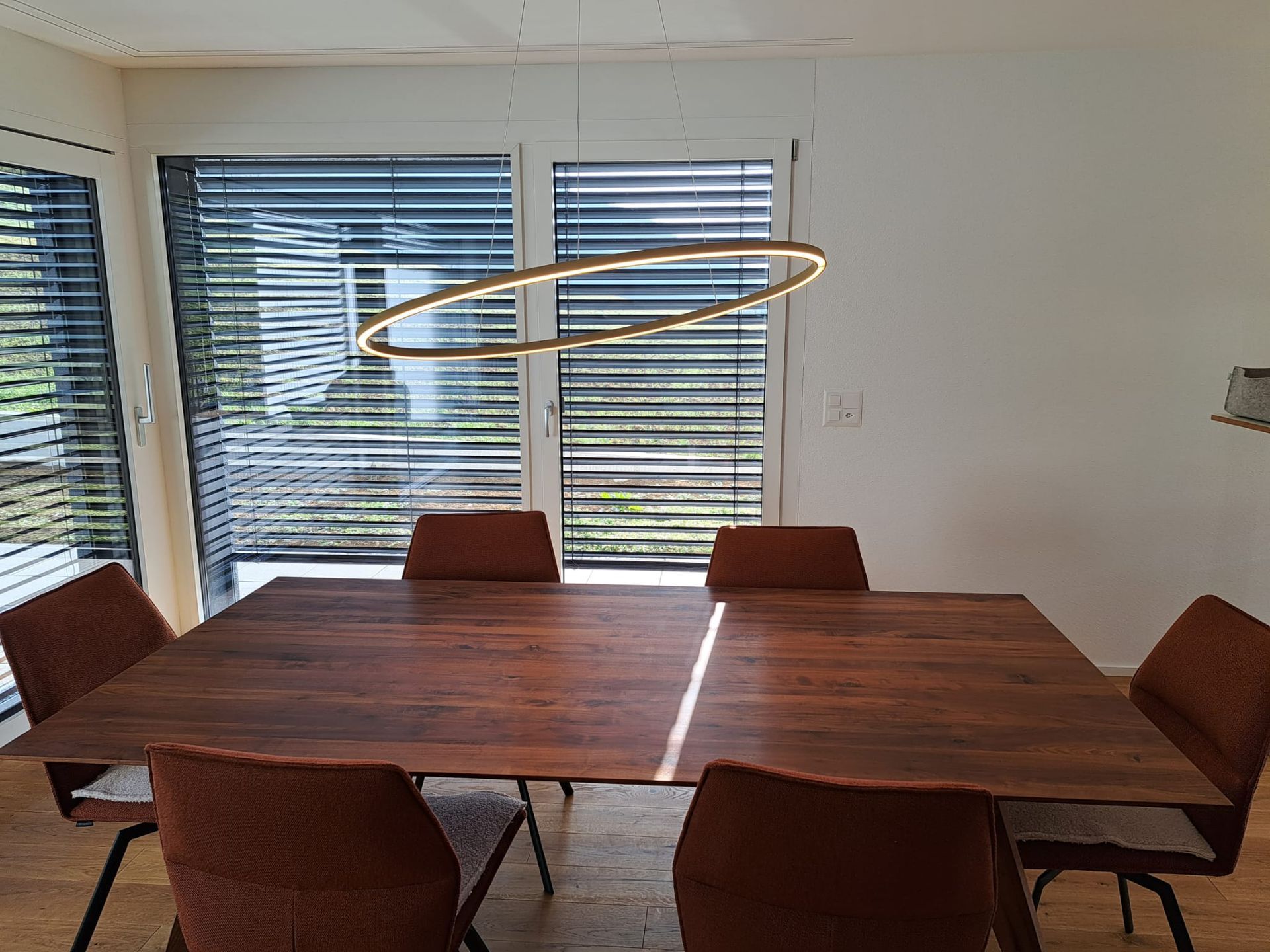 Ein Esszimmer mit einem Holztisch und Stühlen und einem großen Fenster.