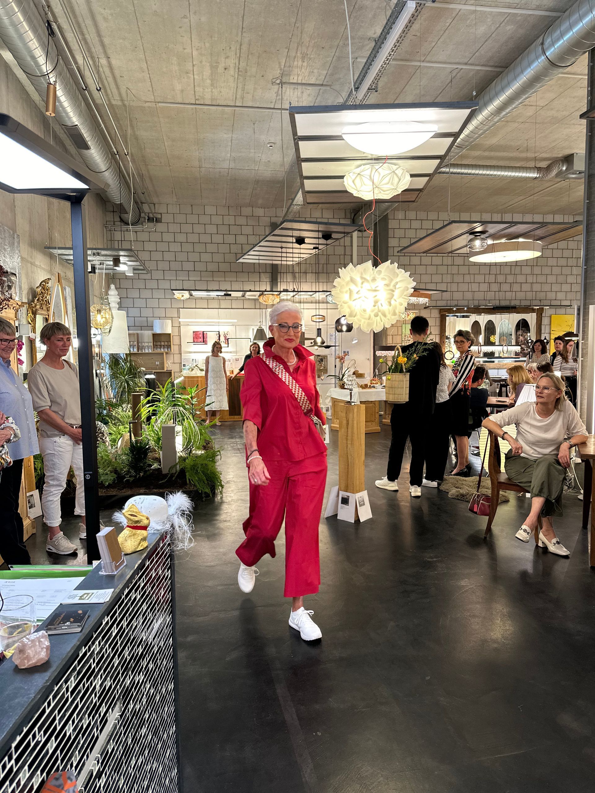 Eine Frau in einem roten Overall geht durch einen überfüllten Raum.