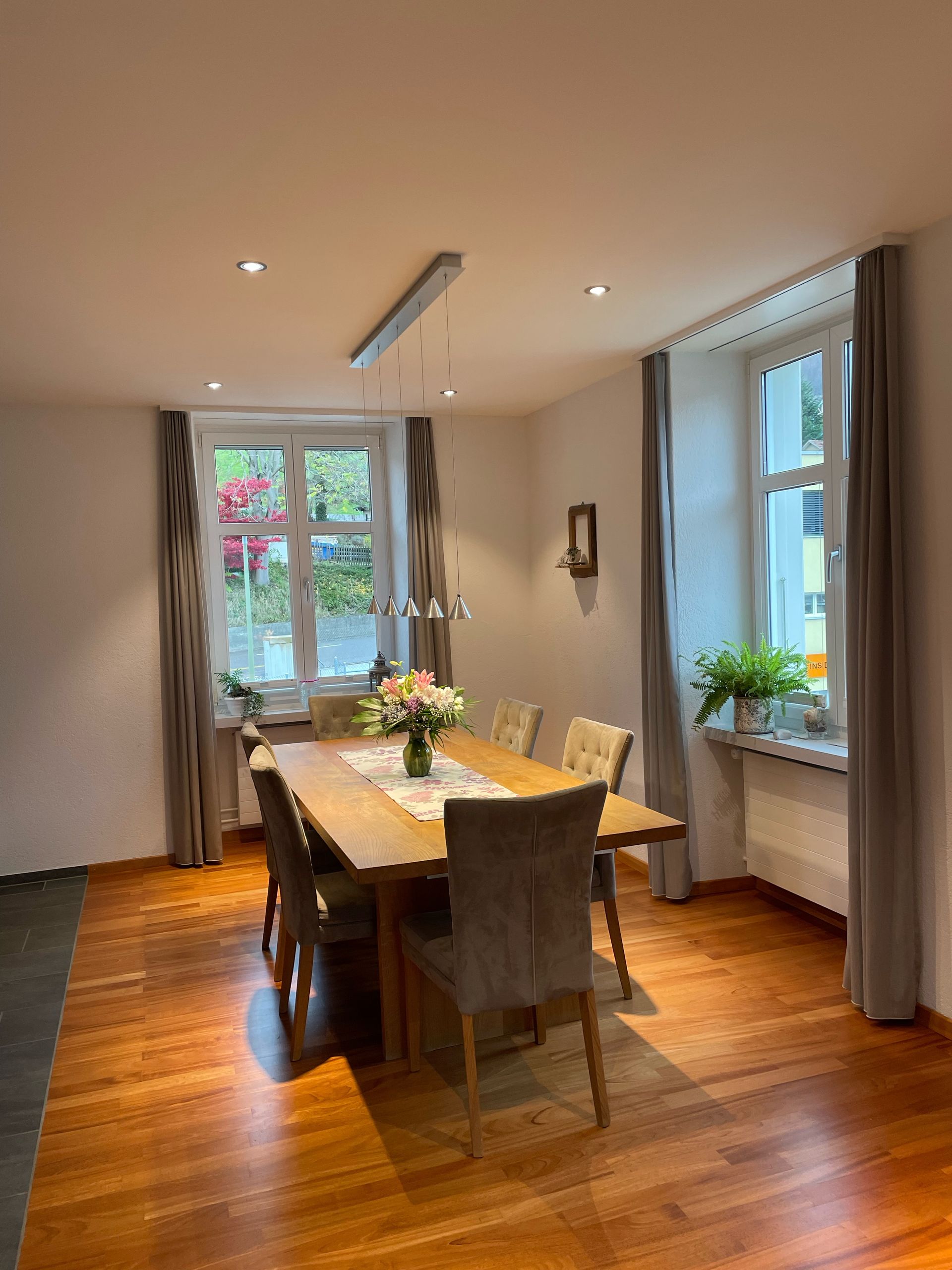 Ein Esszimmer mit einem Holztisch und Stühlen und einem Fenster.