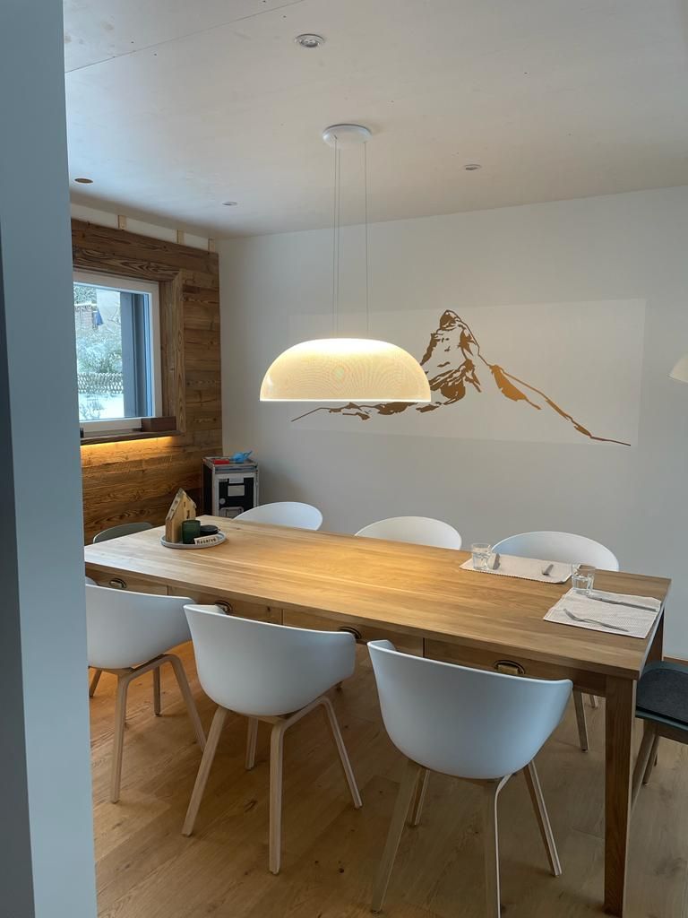 Ein Esszimmer mit einem Holztisch und weißen Stühlen.