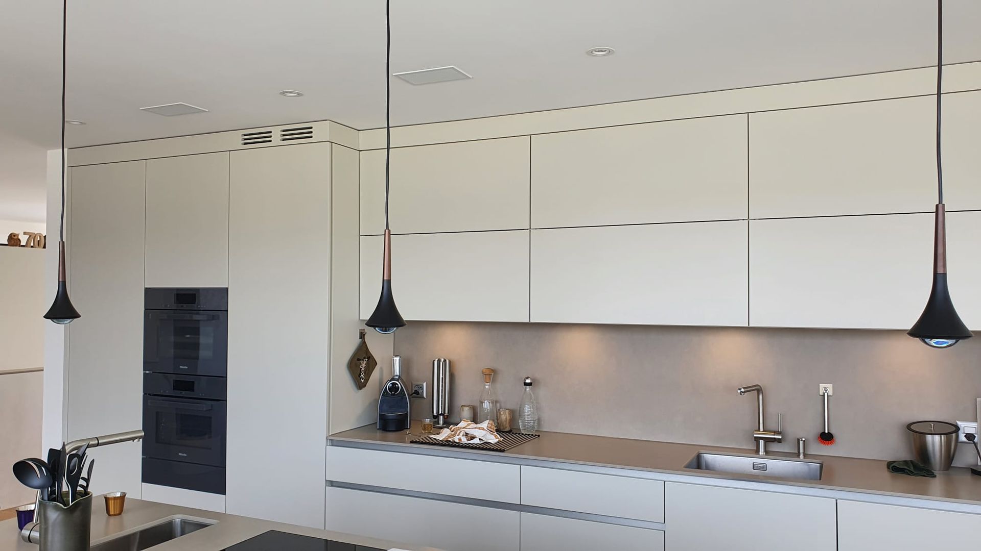 Eine Küche mit weißen Schränken und schwarzen Pendelleuchten