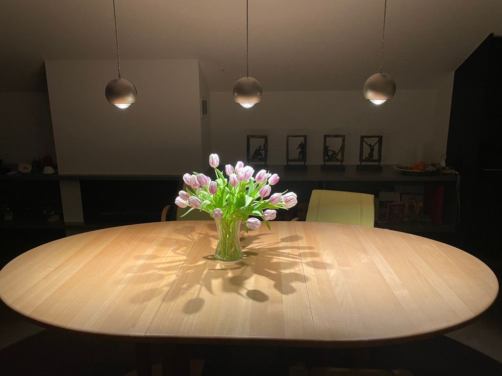 Auf einem Holztisch steht eine Vase mit Blumen.