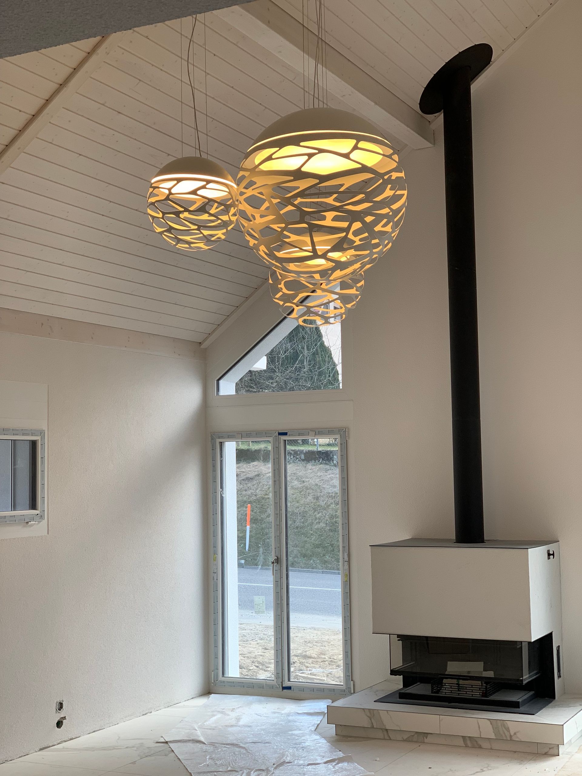 Ein Wohnzimmer mit Kamin und von der Decke hängenden Lampen