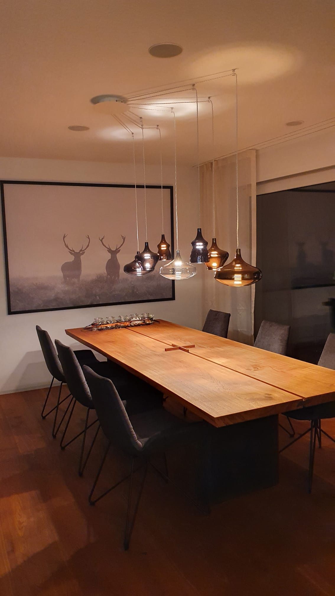 Ein Esszimmer mit einem Holztisch und Stühlen und einem Bild eines Hirsches an der Wand.