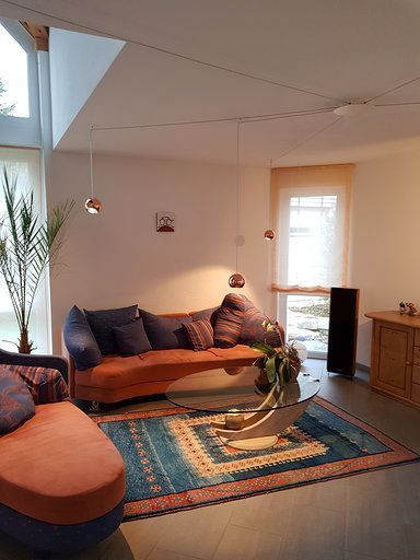 Ein Wohnzimmer mit Couch, Sessel, Couchtisch und Teppich.