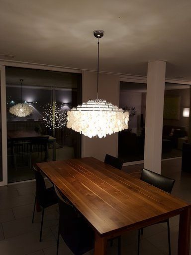 Ein Esszimmer mit einem Holztisch und Stühlen und einem Kronleuchter, der von der Decke hängt.