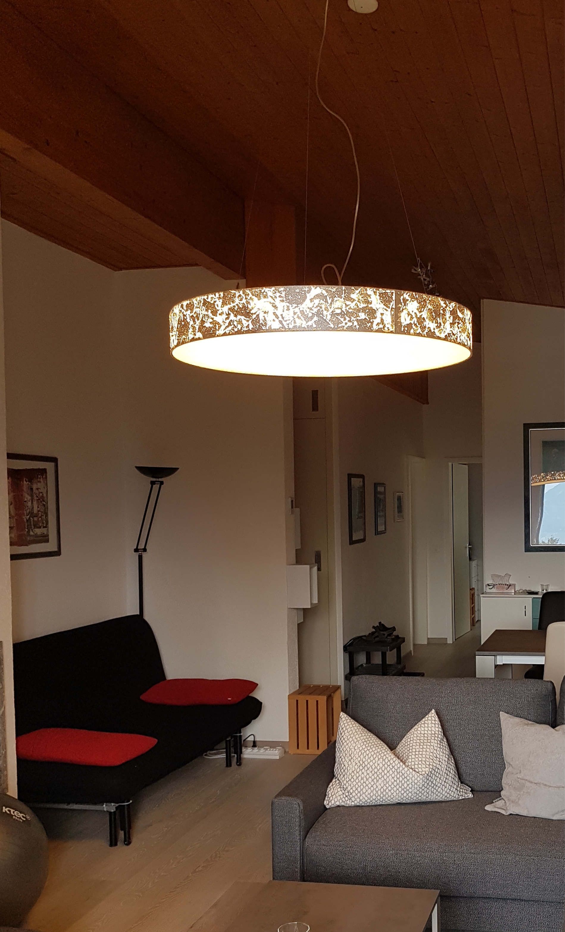 Ein Wohnzimmer mit einer Couch und einer von der Decke hängenden Lampe