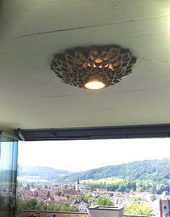 Eine Deckenleuchte hängt von der Decke eines Zimmers mit Blick auf eine Stadt.