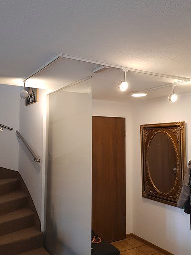 Ein Flur mit Treppe und einem Spiegel an der Wand.