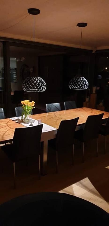 Ein Esszimmer mit einem langen Tisch und Stühlen und einer Vase mit Blumen darauf.