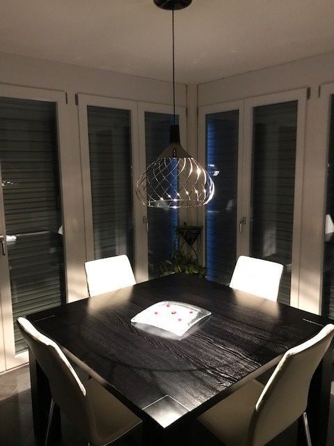 Ein Esszimmer mit Tisch und Stühlen und einer von der Decke hängenden Lampe