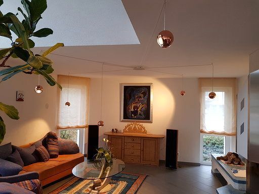 Ein Wohnzimmer mit Sofa, Tisch, Lautsprechern und einem Gemälde an der Wand.
