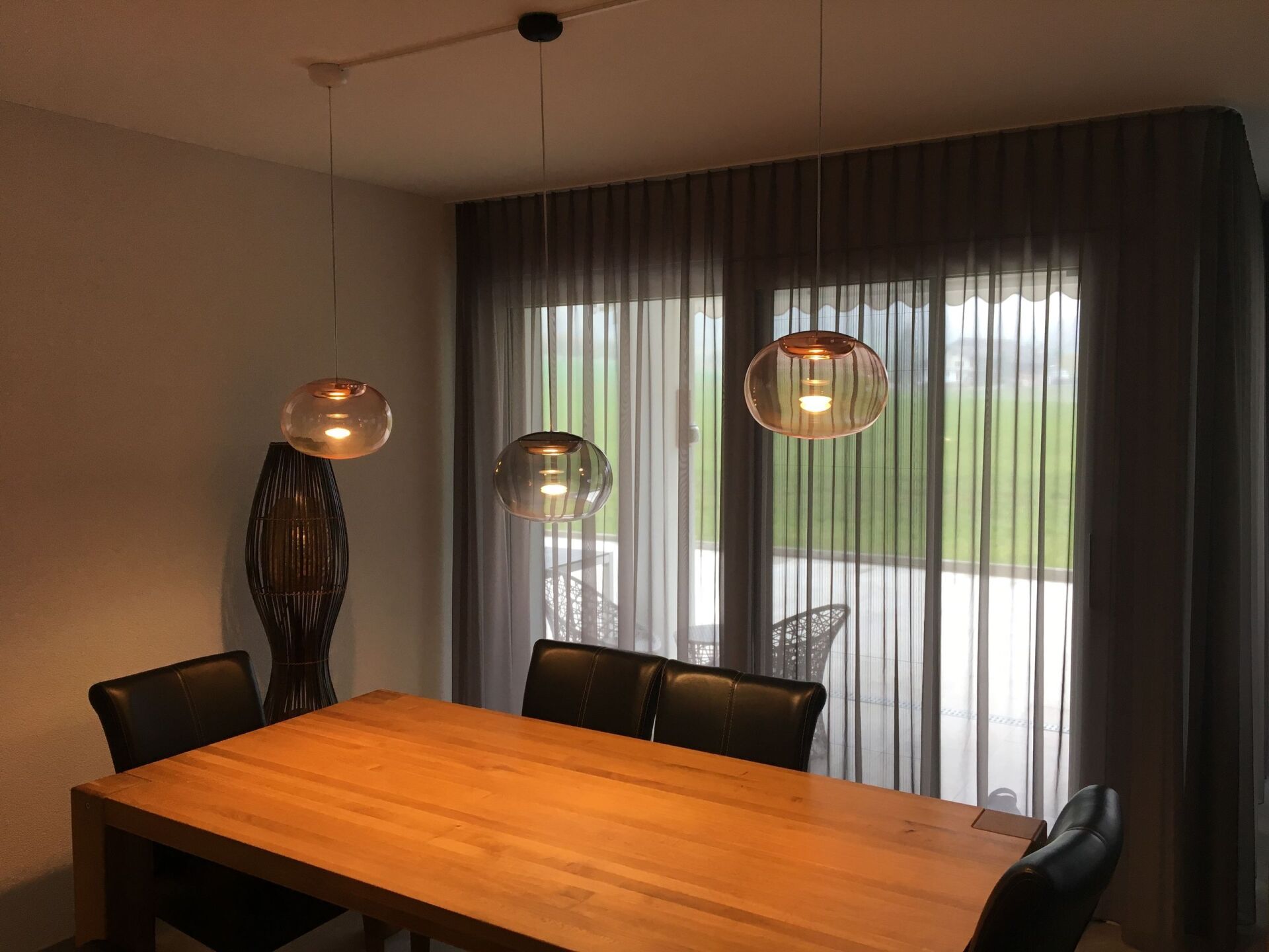 Ein Esszimmer mit einem Holztisch und Stühlen vor einem großen Fenster.