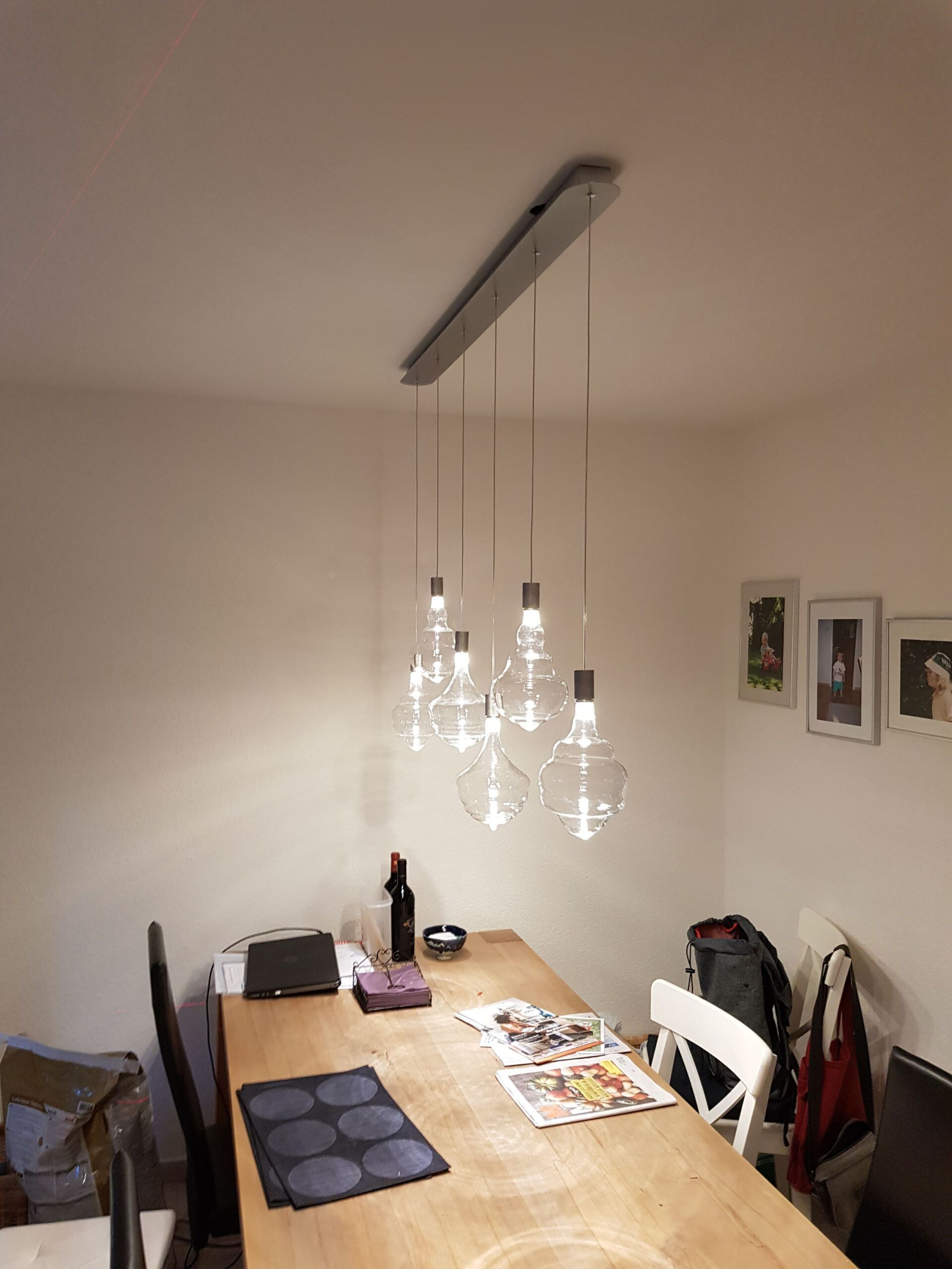 Ein Esszimmer mit einem Holztisch und Stühlen und einem Kronleuchter, der von der Decke hängt.