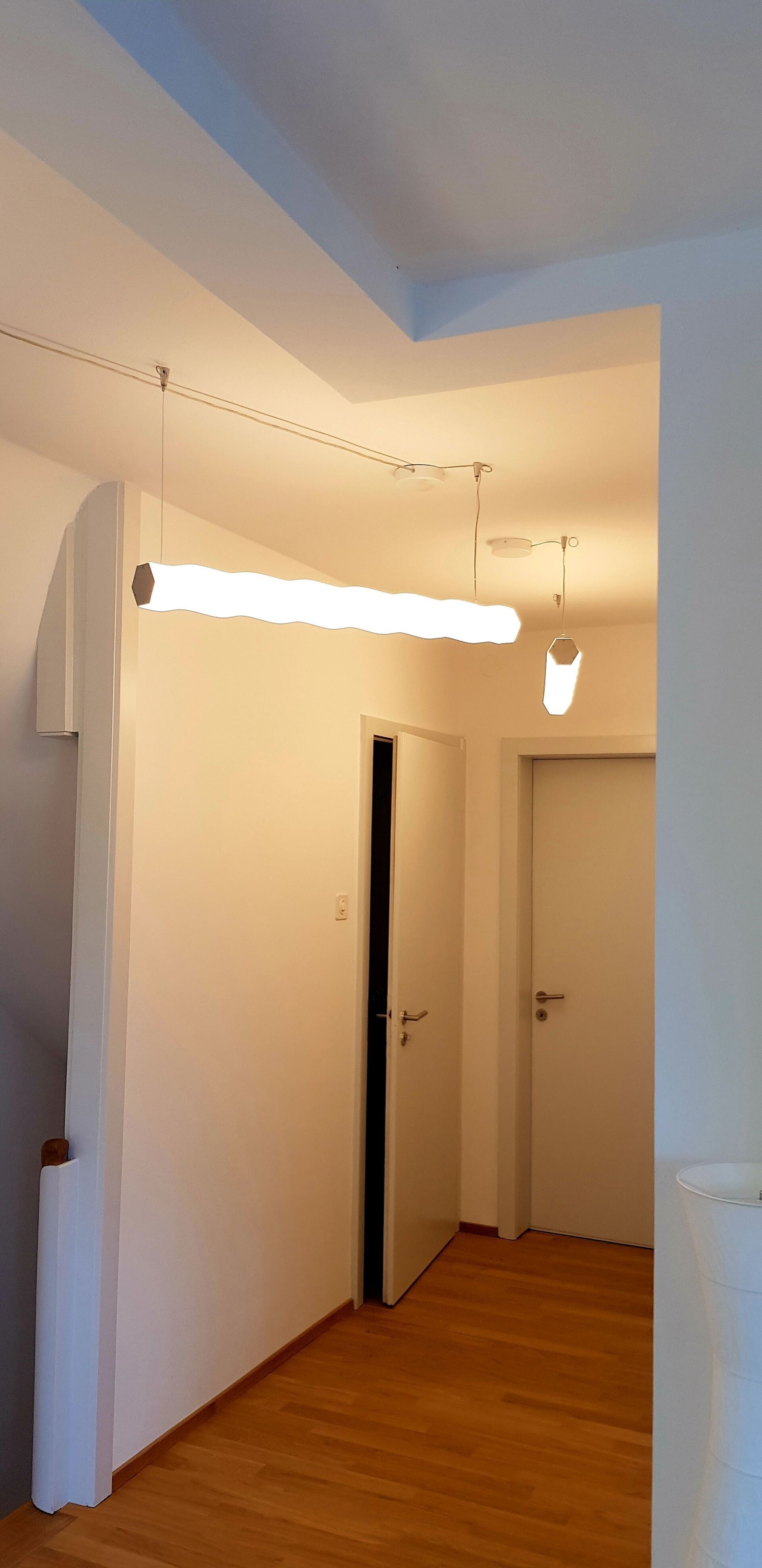 Ein Flur mit einer von der Decke hängenden Lampe und einer Tür.