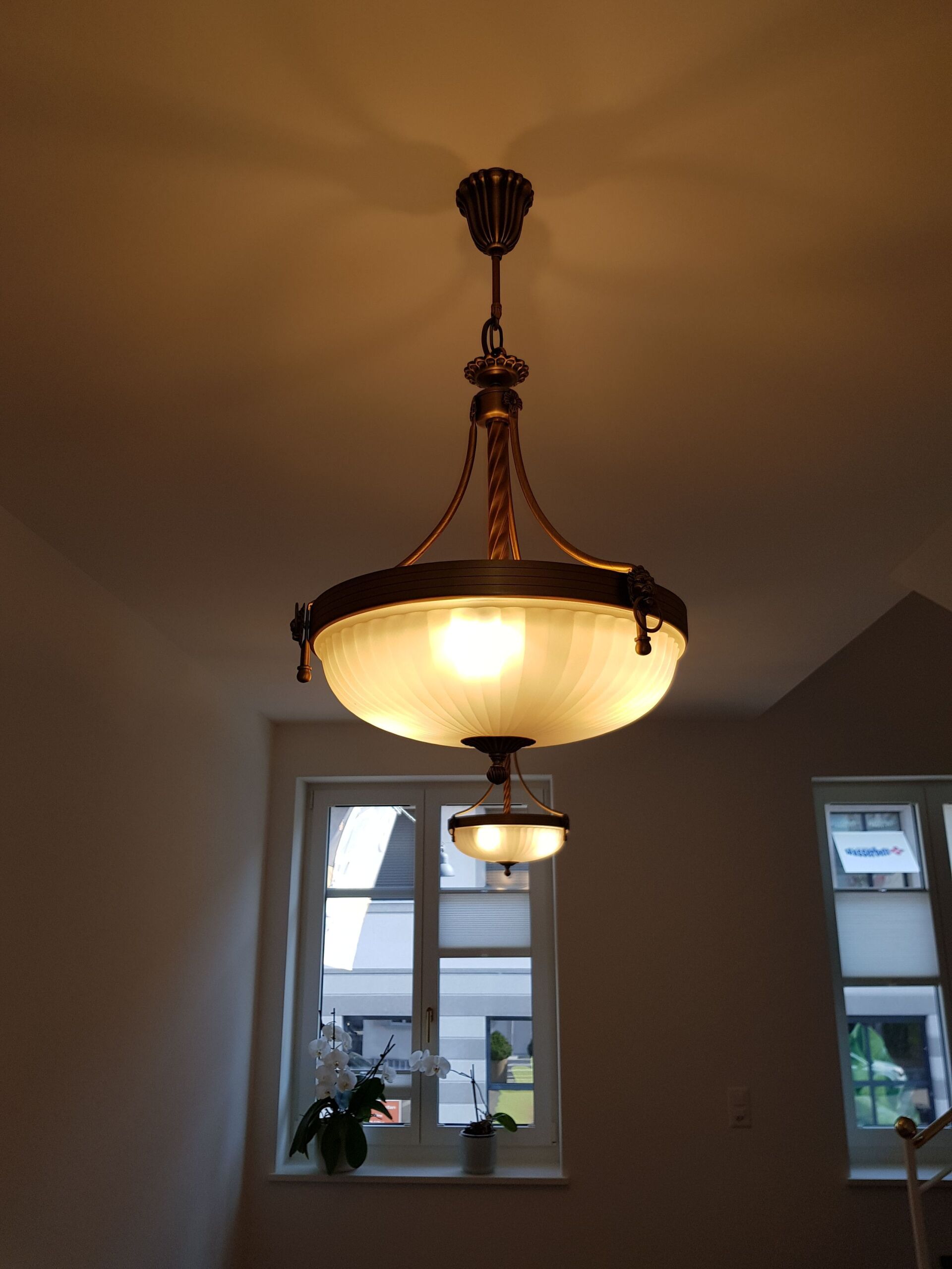 Vor einem Fenster hängt ein Kronleuchter von der Decke.