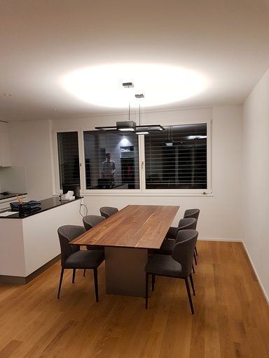 Ein Esszimmer mit einem Holztisch und Stühlen und einem großen Fenster.