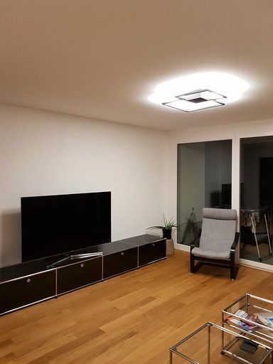 Ein Wohnzimmer mit Flachbildfernseher, Sessel, Couchtisch und Glasschiebetüren.