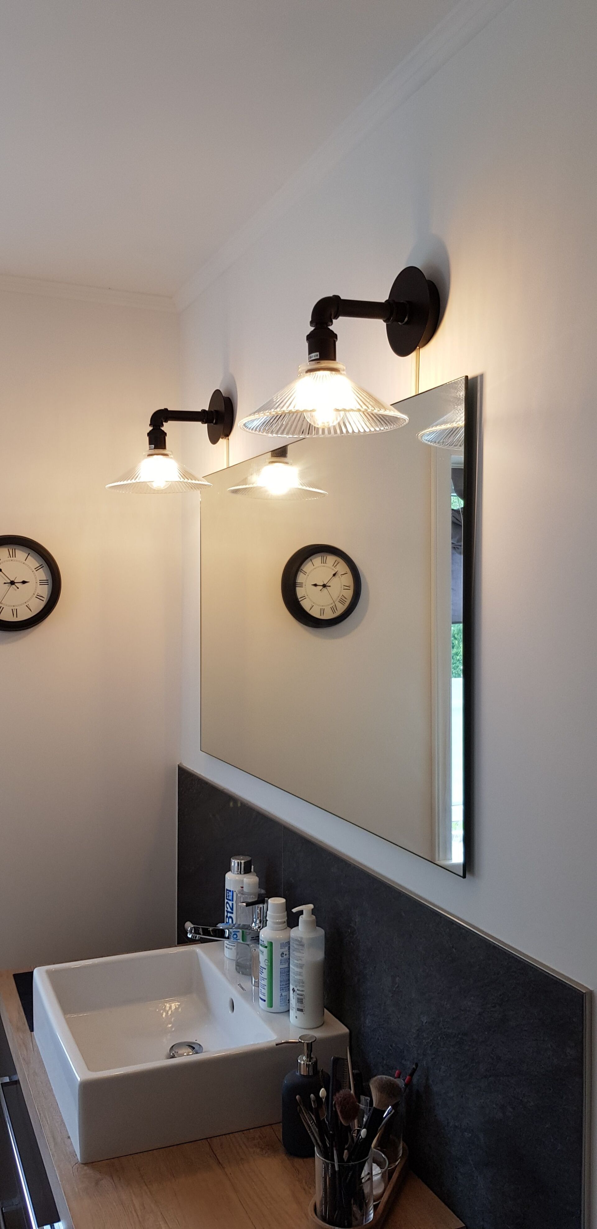 Ein Badezimmer mit Waschbecken, Spiegel und Uhren an der Wand.