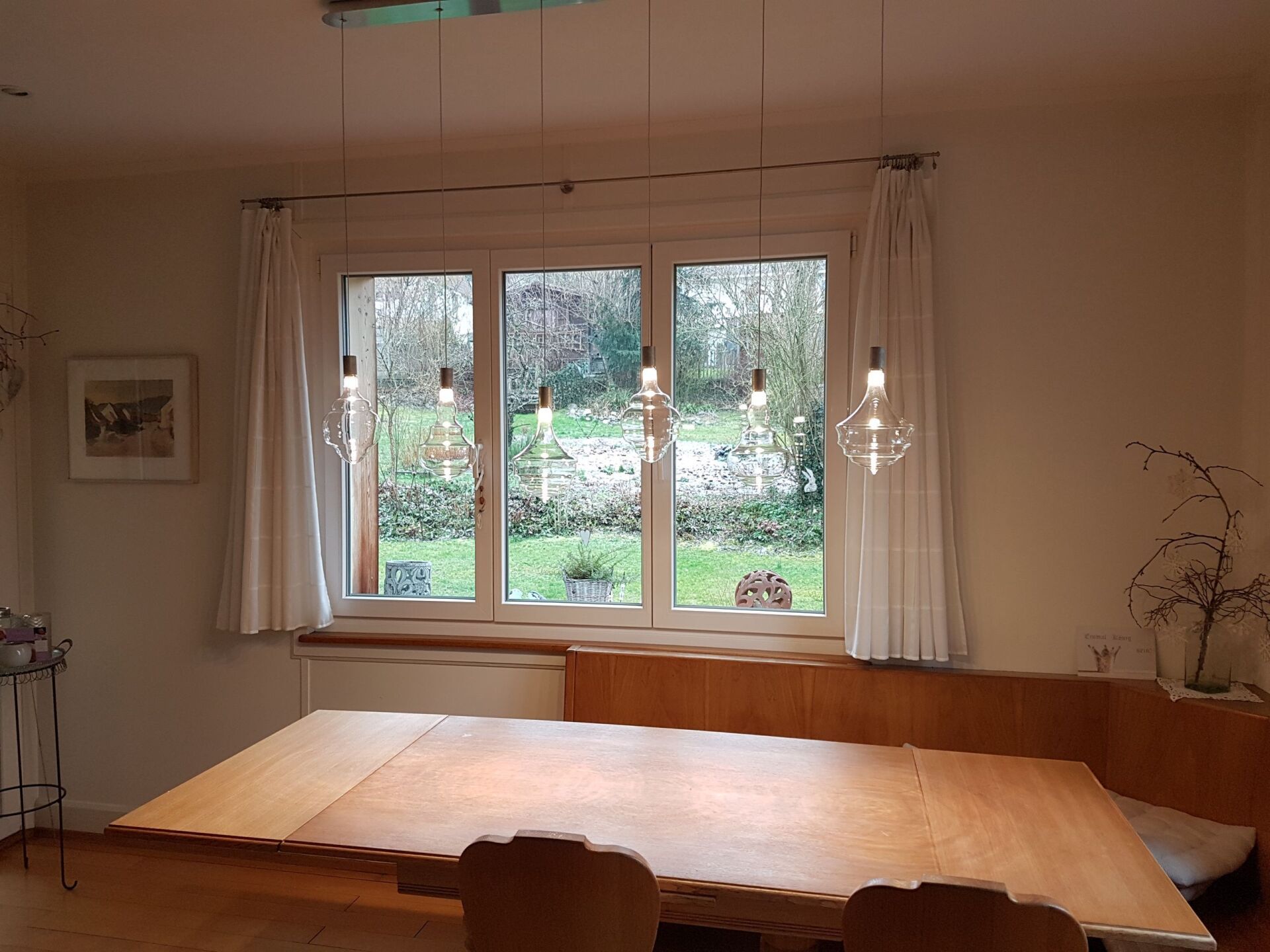 Ein Esszimmer mit einem Holztisch und Stühlen und einem großen Fenster.