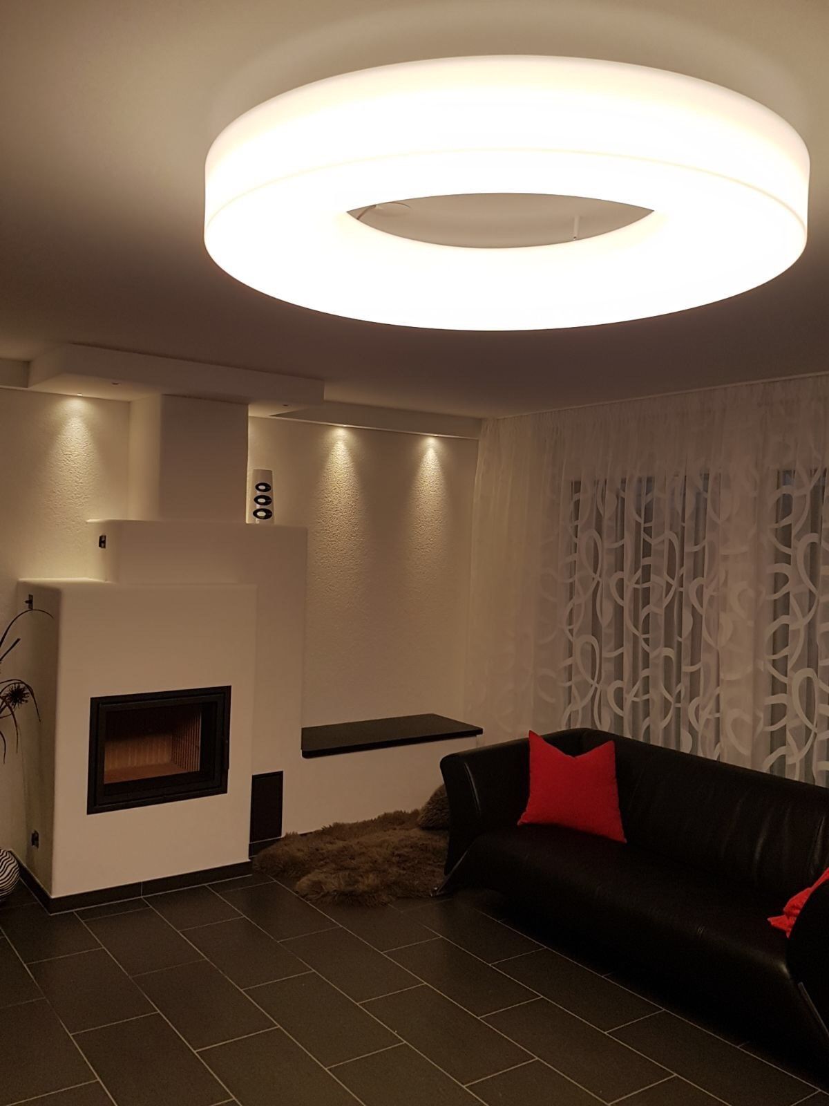 Ein Wohnzimmer mit einer Couch und einem Kamin sowie einer großen Lampe, die von der Decke hängt.