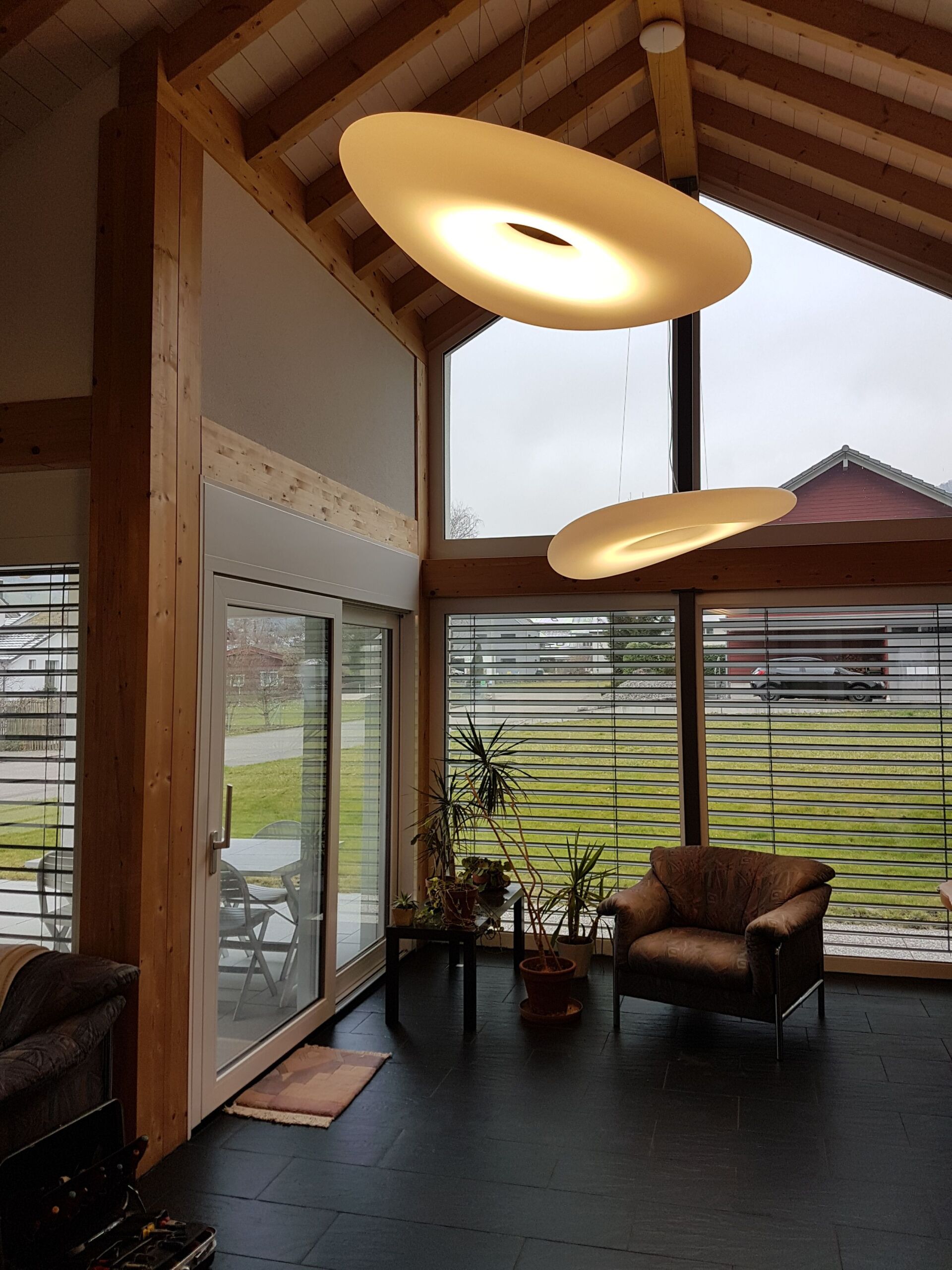 Ein Wohnzimmer mit vielen Fenstern und einem Stuhl