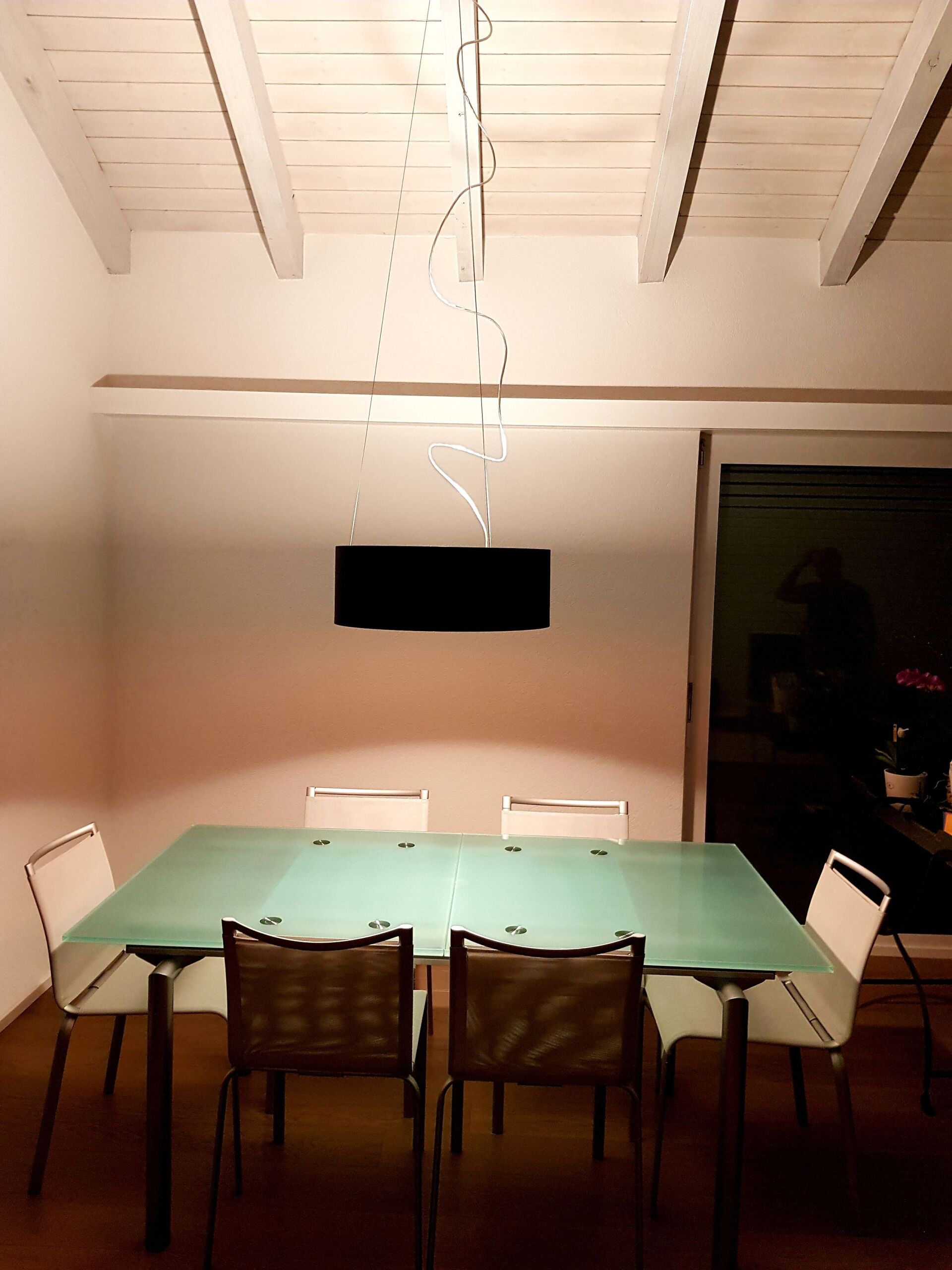 Ein Esszimmer mit Tisch und Stühlen und einer von der Decke hängenden Lampe