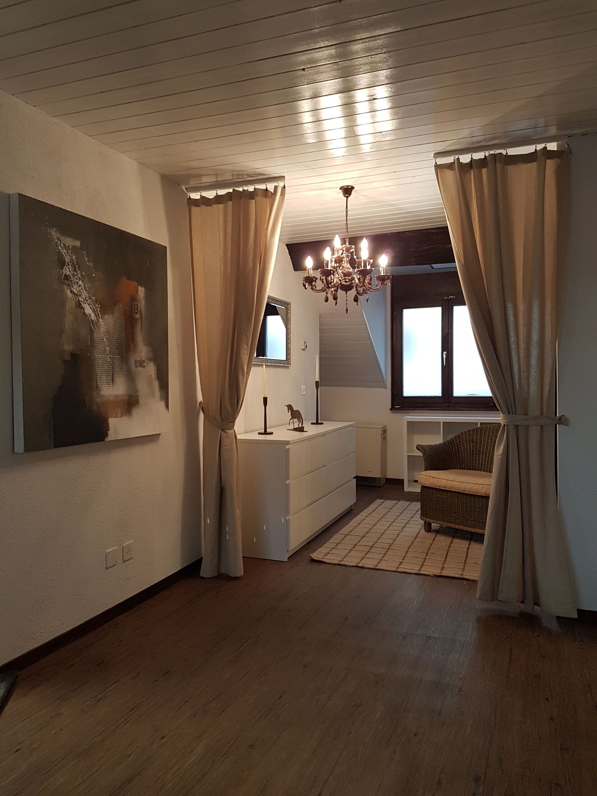 Ein Wohnzimmer mit einem Kronleuchter und einem Gemälde an der Wand